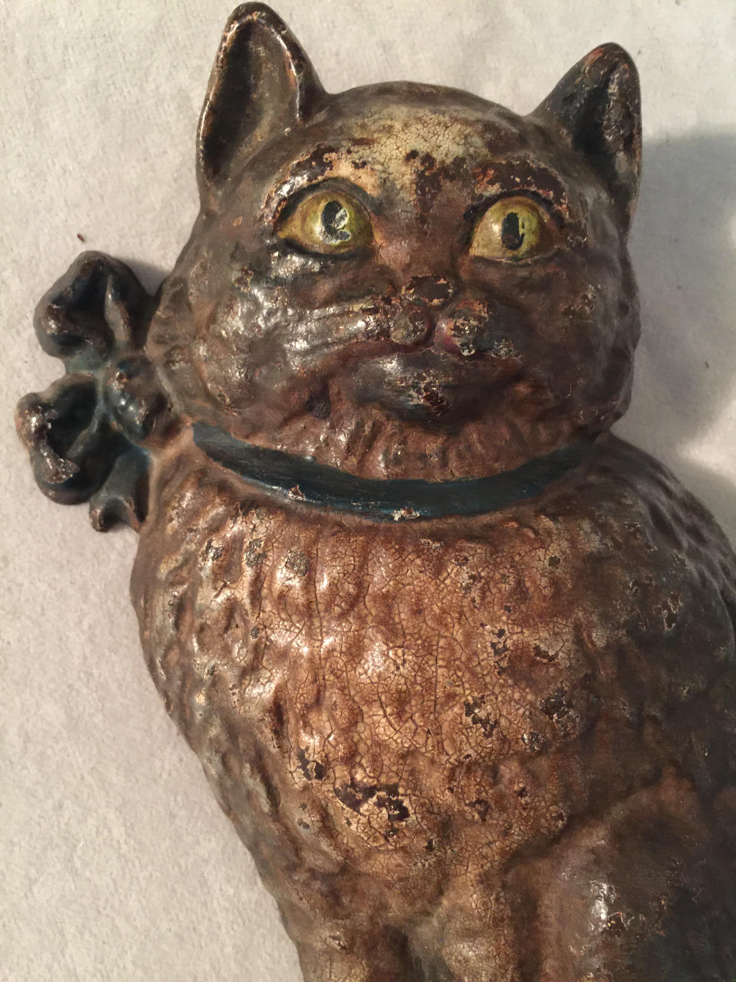 Cast iron doorstops are one of the most adored collectibles produced here in the U.S.A for several decades. Some of the most sought after examples are the animals. Here we have just that. This cat with the cute expression, ribbon collar, and