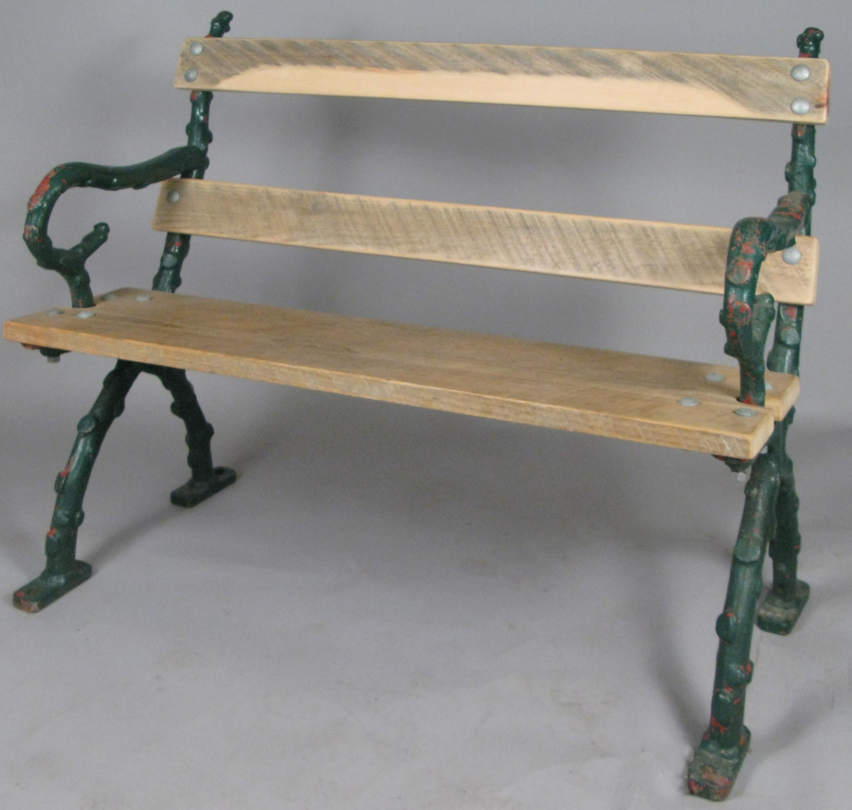 A very well made and handsome antique early 20th century garden bench from Bath, England. The cast iron frame is made in a branch design, and the wooden seat and back have been recently replaced.