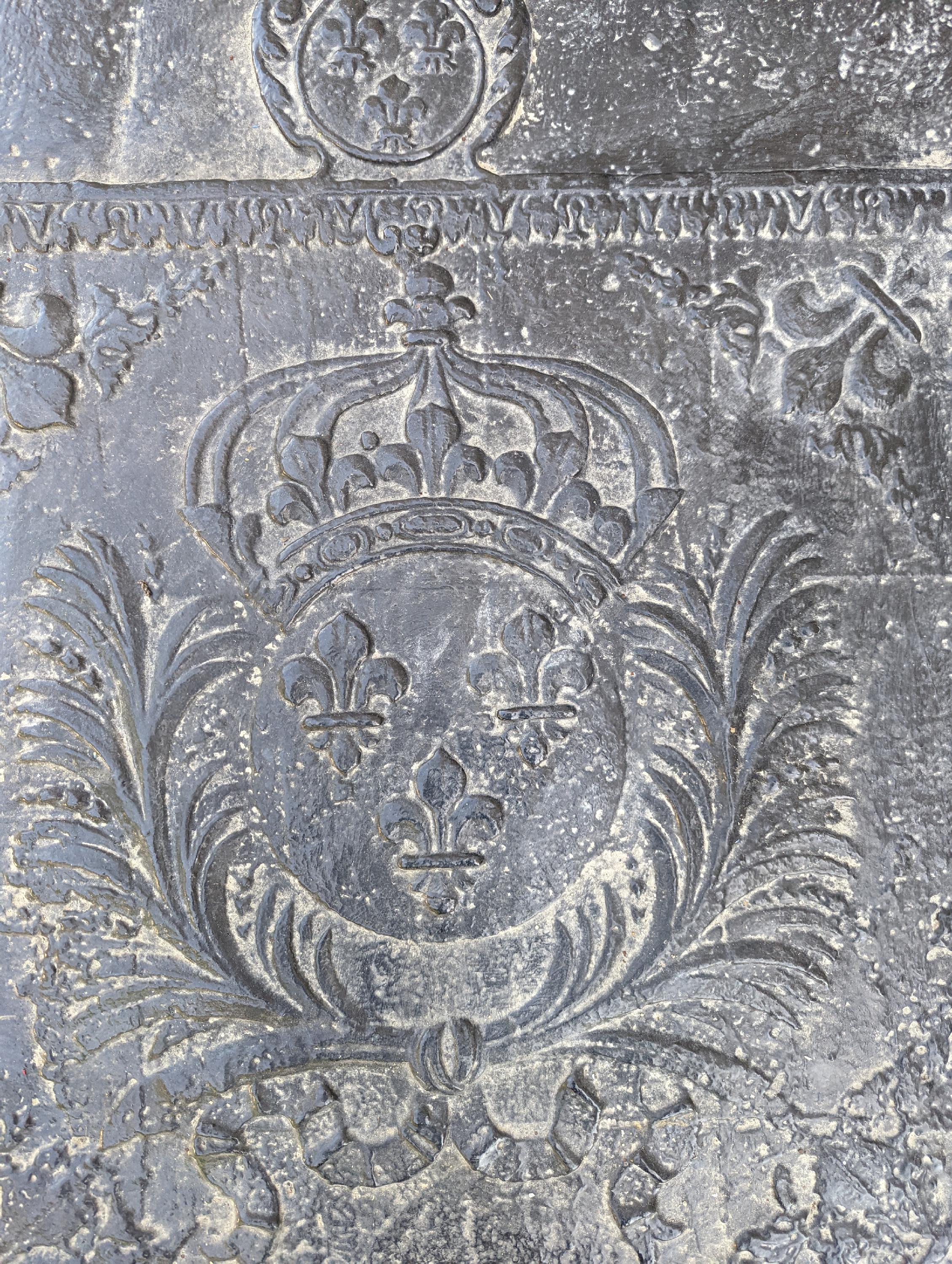 Cette plaque de cheminée aux armoiries françaises, d'une taille exceptionnelle, a été réalisée au XVIIIe siècle. Au centre d'un cadre figurent les armoiries principales, d'azur avec trois fleurs de lys d'or, surmontées d'une couronne royale. Elles