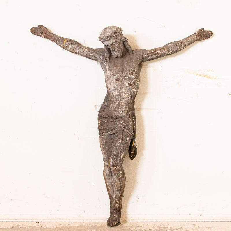 The aged, weathered gray patina reveals distress throughout this antique cast iron crucifix, yet adds to the powerful impact of the suffering Christ figure. One's gaze rests on the face of Christ and the crown of thorns encircling His head. This