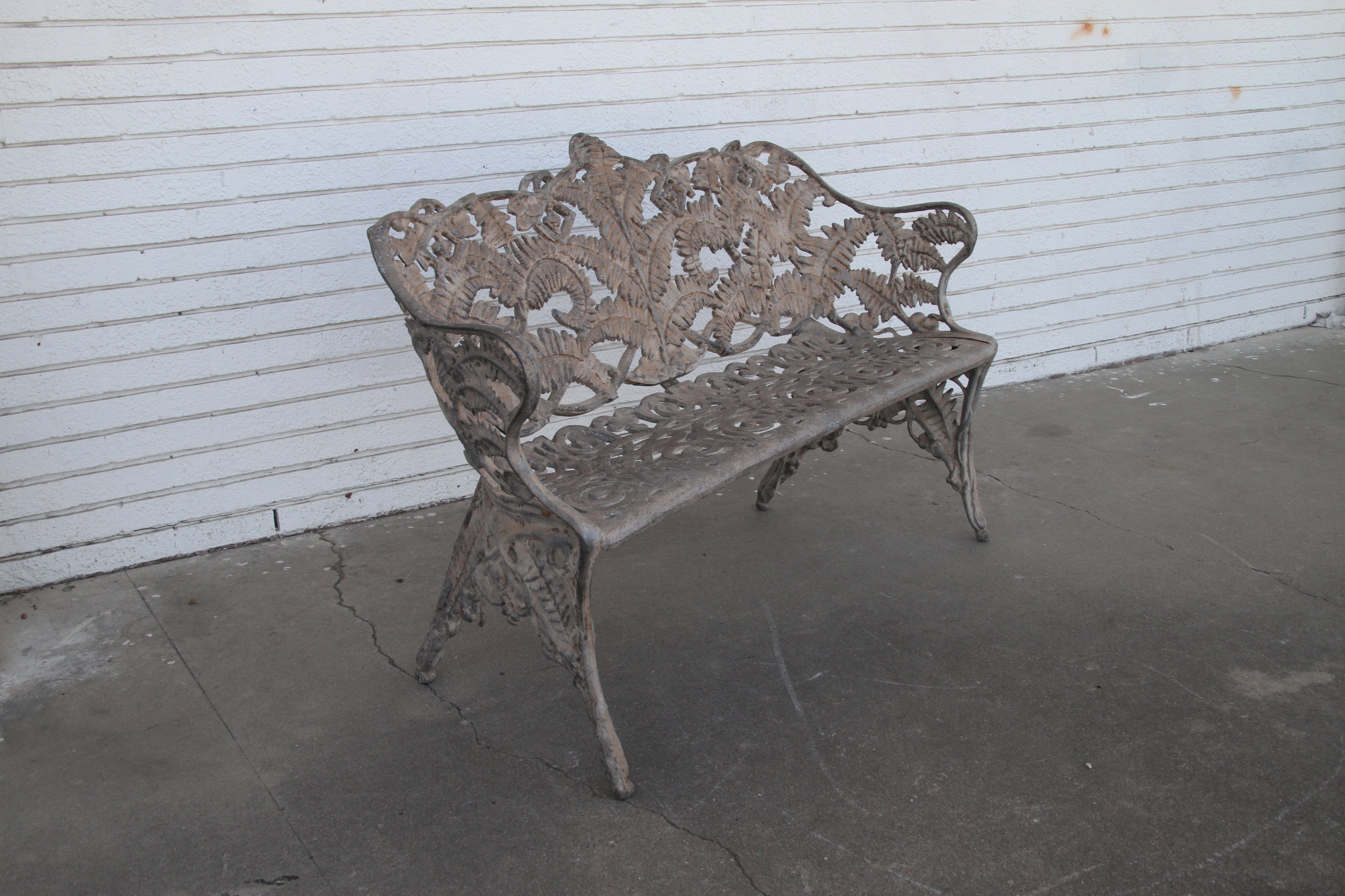 Antique cast iron patio settee.

An Antique cast iron garden bench from the early 20th century.
Scroll design on the seat and the back that features a fern motif.

We also have a matching arm chair in last photo.