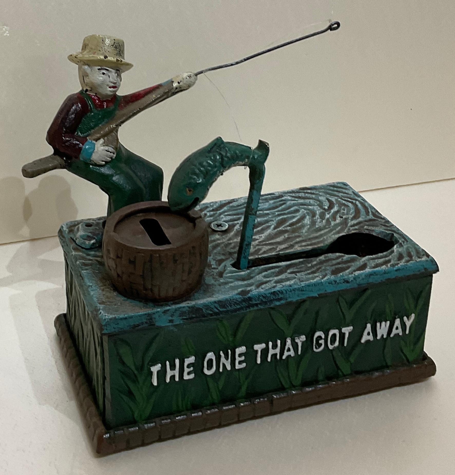 A nice sized Early 20th century American cast iron piggy, penny bank or money box. This decorative bank features a boy fishing and obtains its original antique painted patina. Funny marking 