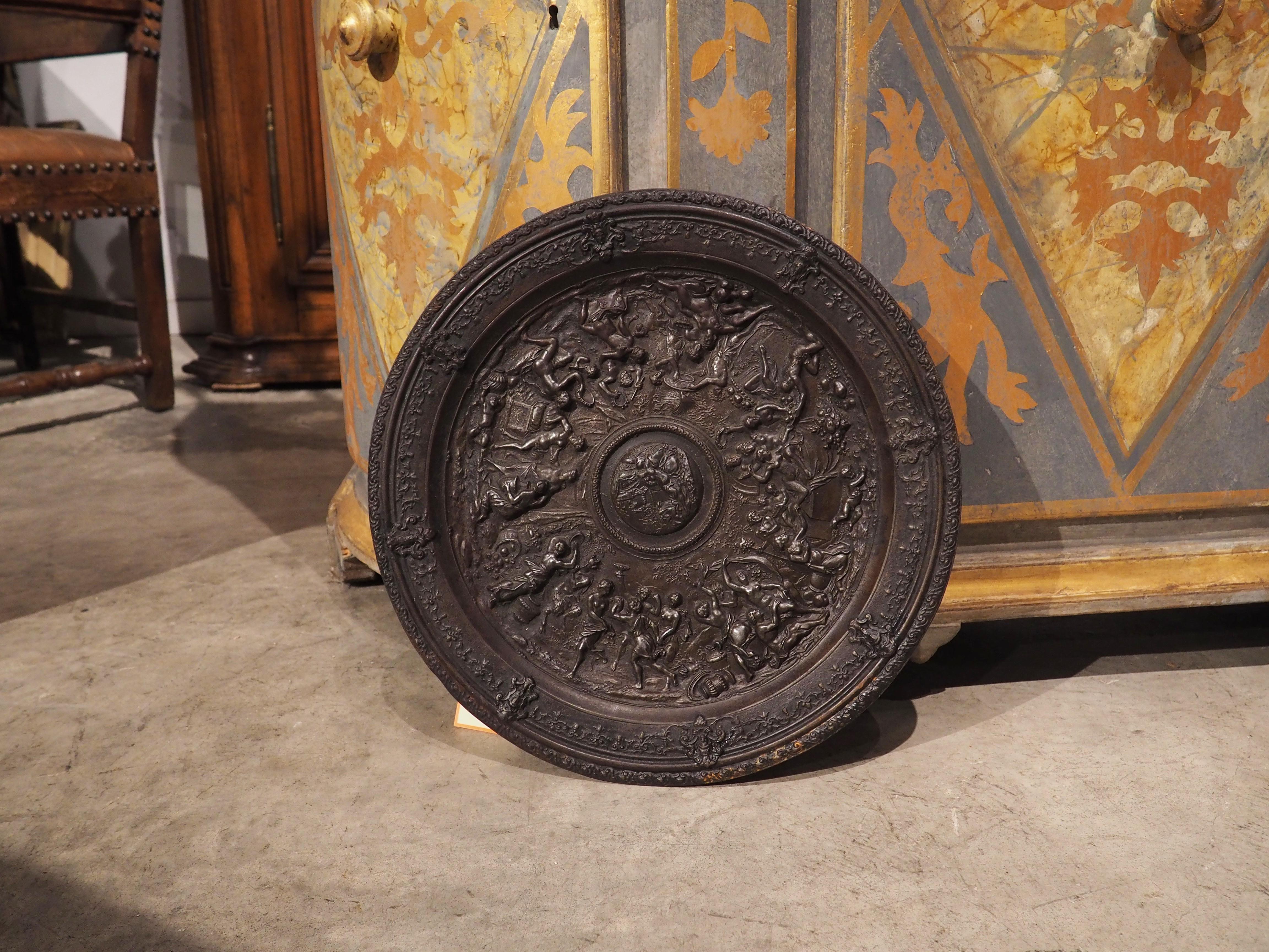 This cast iron charger from Germany was hand-worked in the 1800s. The low-relief image, in this case, a Bacchanalian scene, is full of hundreds of small decorative and figurative details.

The main body of the charger is recessed below the outer
