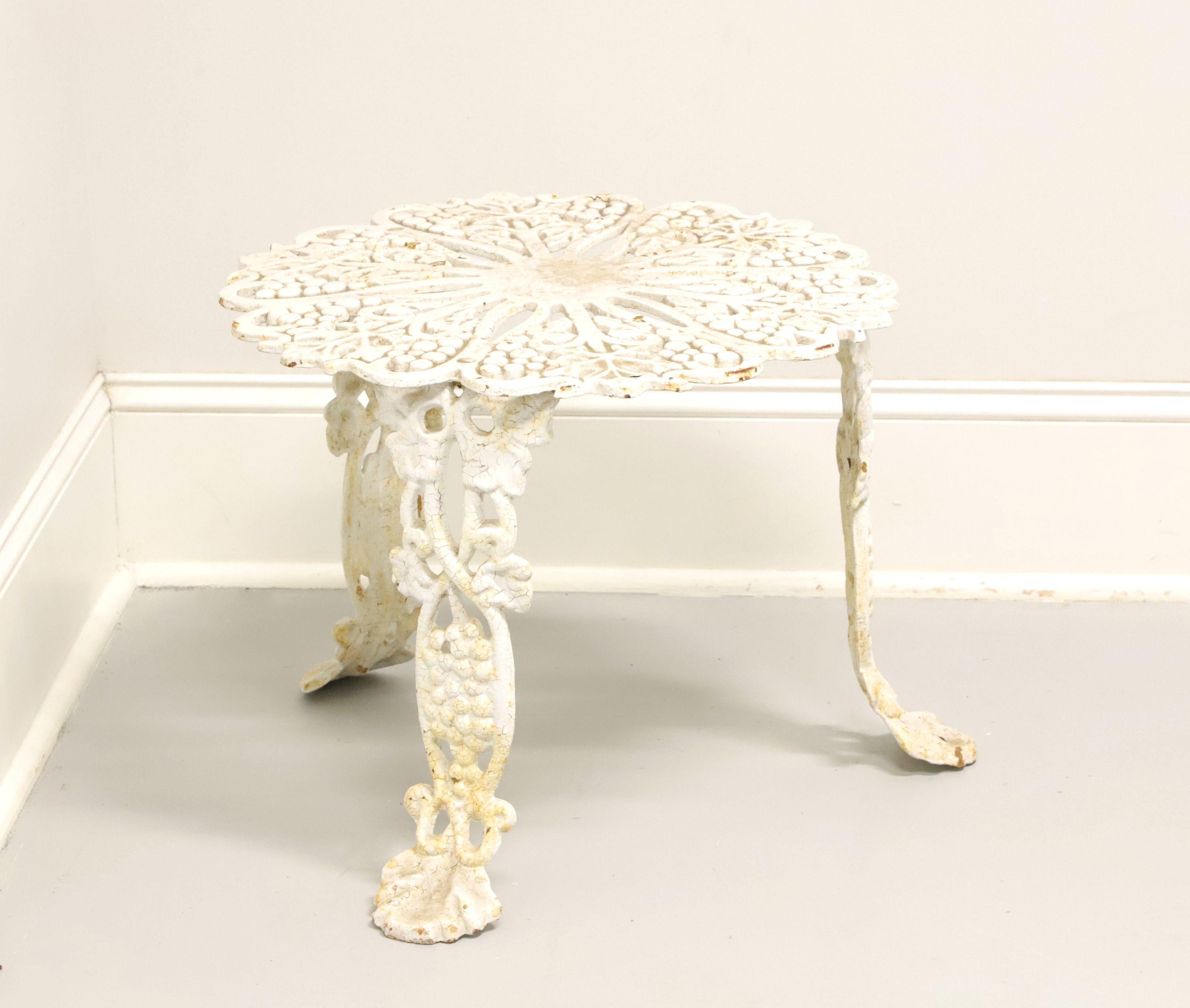 An antique Victorian style grape leaf motif round garden patio side table, unbranded. Cast iron construction in a pierced Rococo design, scalloped edge top, and three legs. Ready for a fresh coat of paint or use as-found. Made in the USA, in the