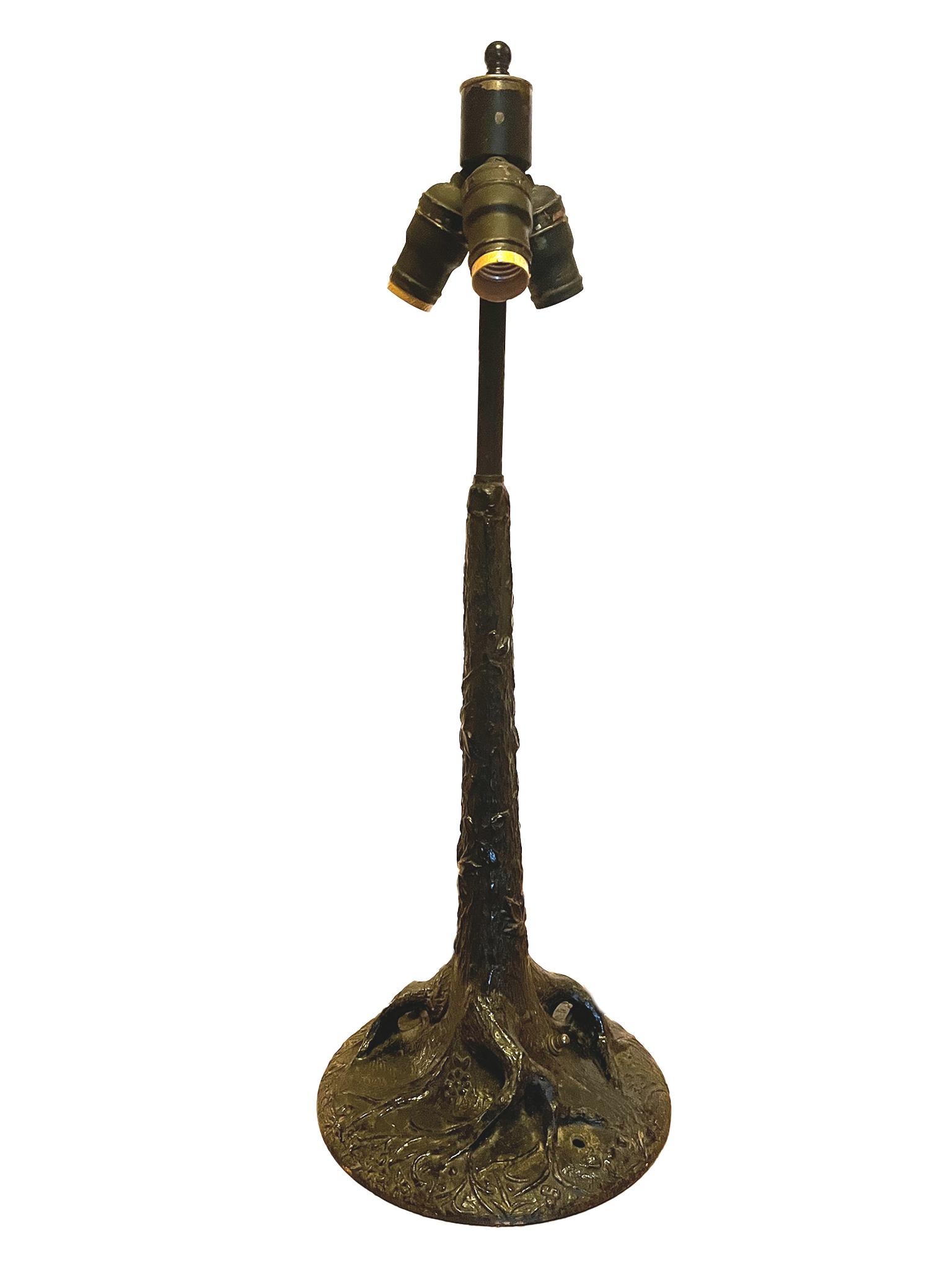 This whimsical table lamp was made in the Early 20th Century. It is cast iron shaped in the form of a tree, complete with gnarled roots and vine-adorned trunk. The lamp is newly rewired and paired with a new custom-fitted linen shade. It has a
