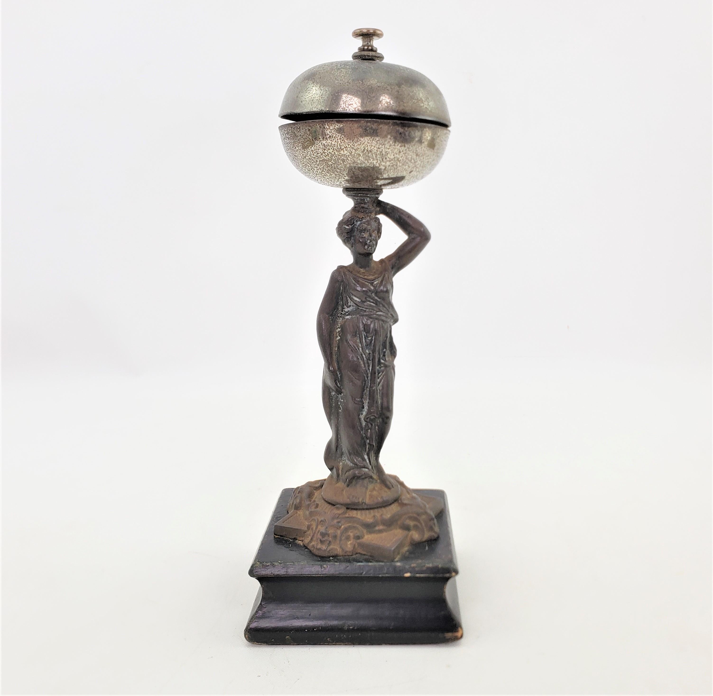 This antique dinner or service counter bell is unsigned, but presumed to have originated from England and date to approximately 1900 and done in the period Edwardian style. The bell features a cast metal robed female holding up and two piece plated
