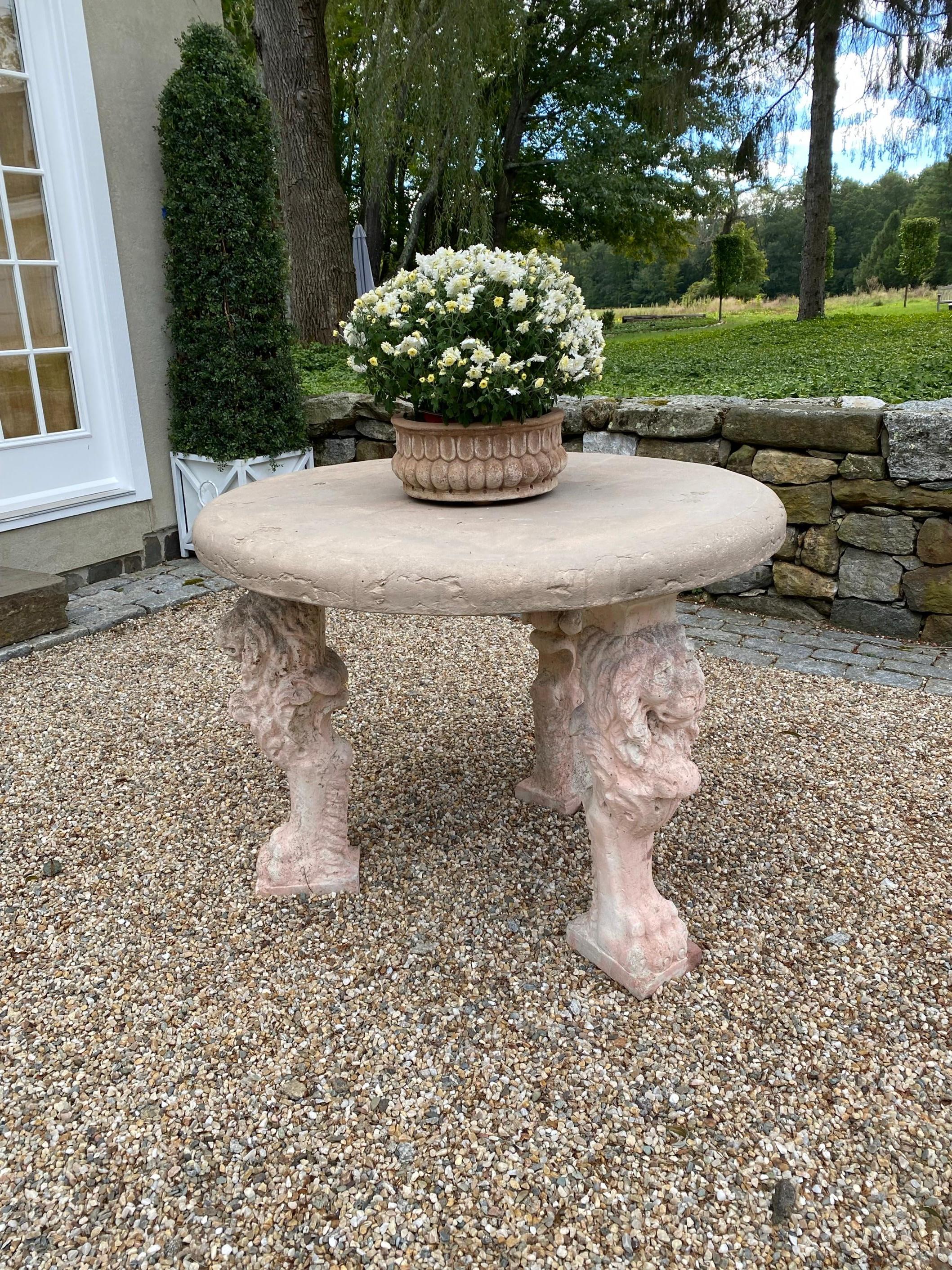 A stately round cast stone table top supported by 3 cast stone lion figured legs. The table has wonderful aged patina and character only time can produce.  be used as a garden sculptural object or an entry foyer center table.
Table shows aged