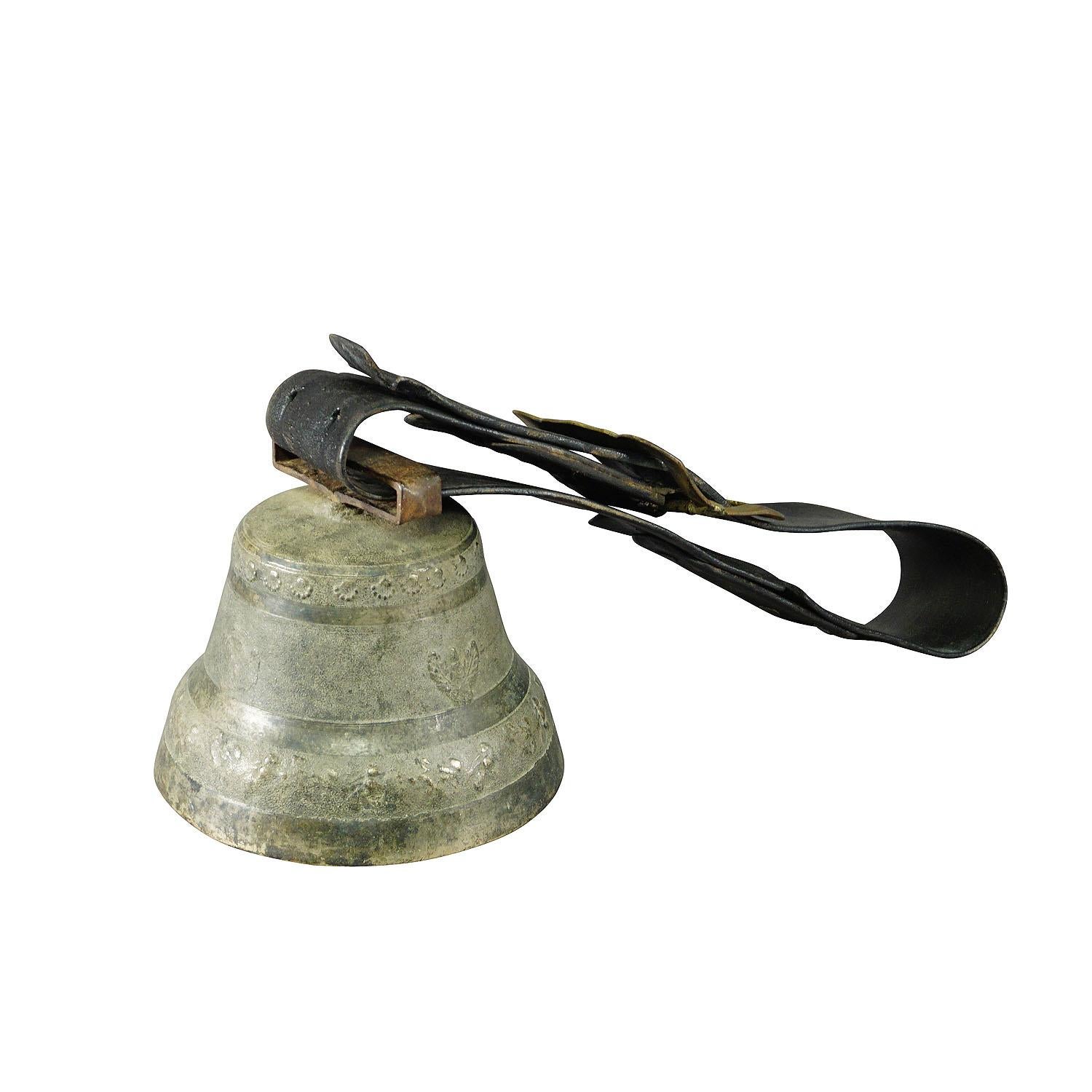 A large and heavy casted bronze cow bell manufactured in Switzerland around 1930. The antique bell features high relief motifs of farm animals, human heads and foliages. The bell comes with its original brown leather strap with buckle. Bells like
