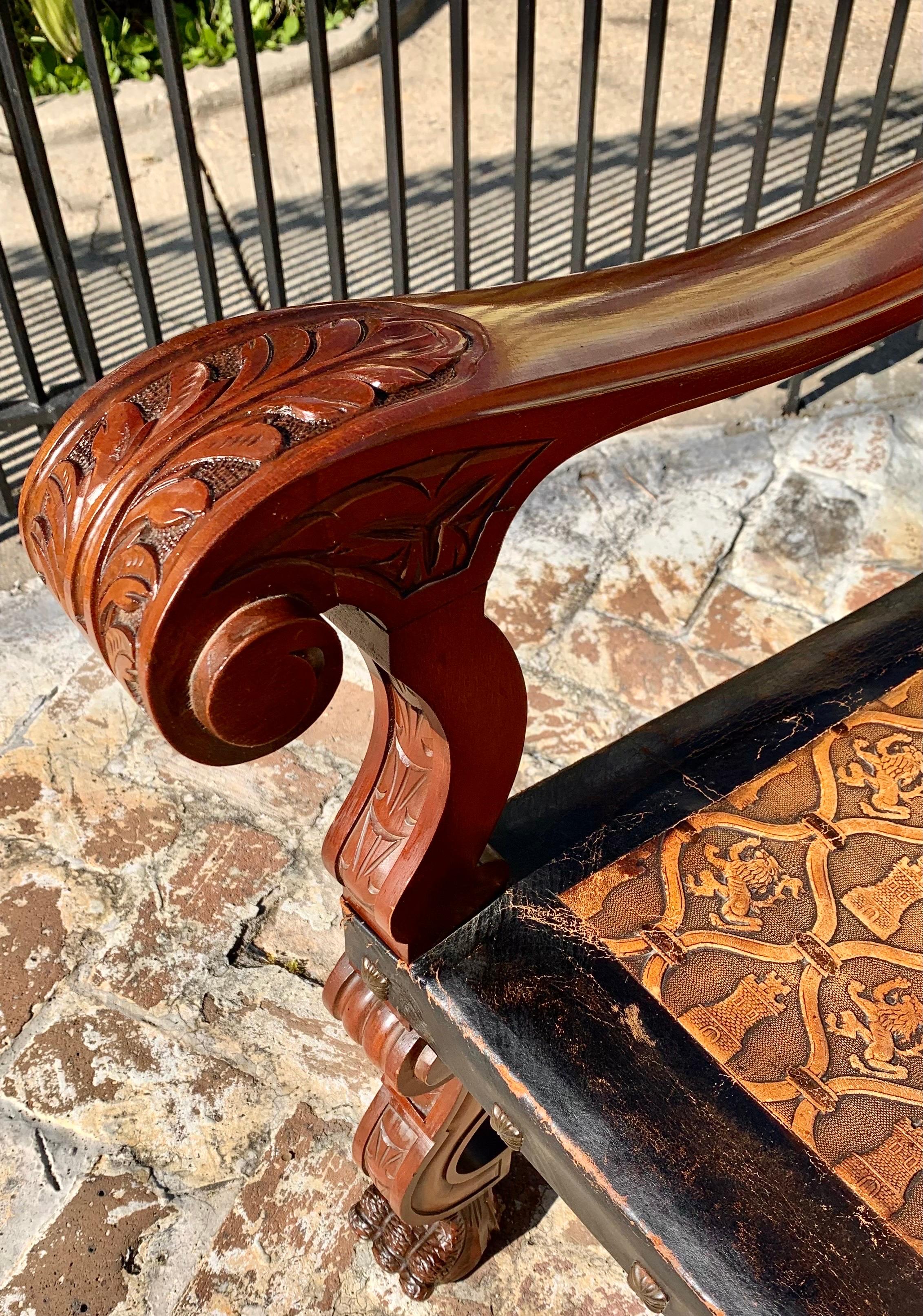 Ancien fauteuil castillan en acajou sculpté à la main et en cuir délicieusement gaufré, avec un beau profil sculpté d'un Conquistador espagnol dans la partie supérieure de la crête. Les bras sont sculptés de feuilles d'acanthe et les pieds de pattes