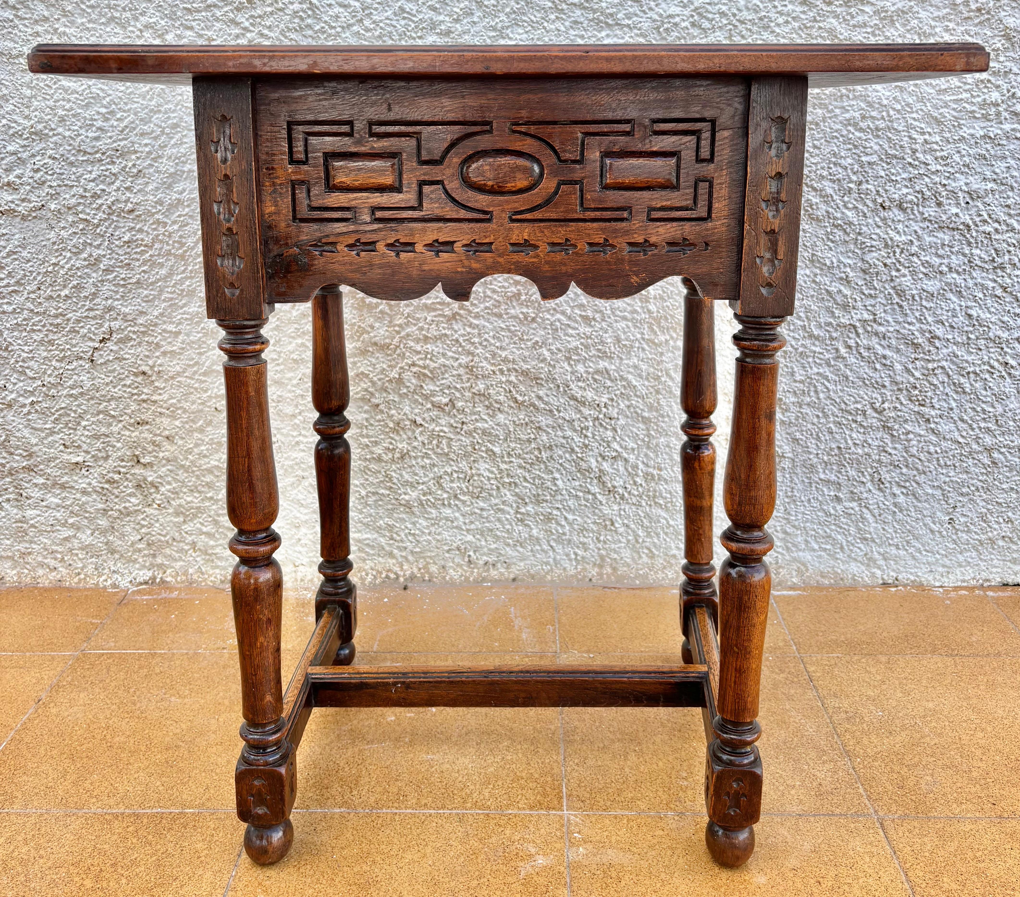 Beautiful Spanish Castilian style side table featuring a single drawer and intricate carved panels, dating from the early to mid-20th century. The front and sides display geometric and circular motifs deeply carved into the wood, characteristic of