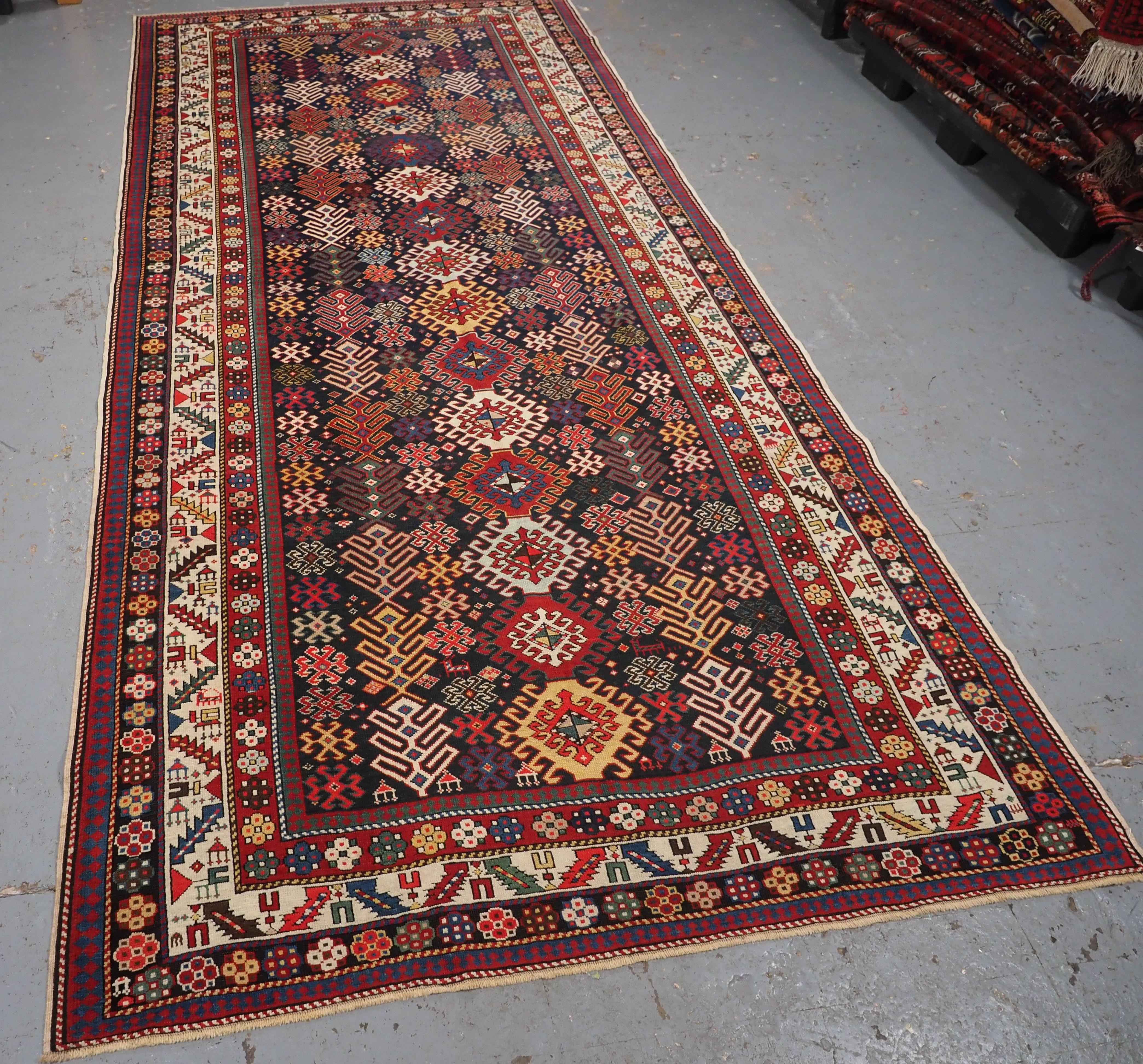 Size: 11ft 0in x 4ft 11in (335 x 150cm).

Antique Caucasian Dagestan long rug with hooked medallion design.

Circa 1890.

A superb example of a Dagestan long rug, the central row of multi coloured hooked medallions are on a dark indigo blue field,