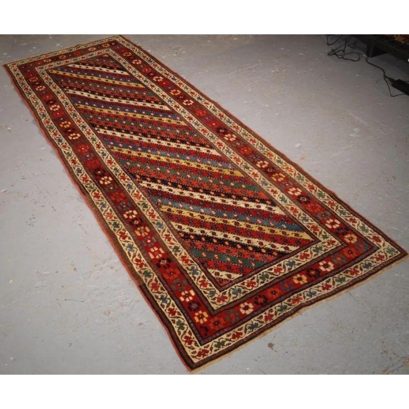 A superb example of a Gendje long rug with multi coloured diagonal stripes in superb natural colours giving the rug a very light feel. The rug is framed by a classic but simple floral rosette border.

The rug is in excellent condition with slight
