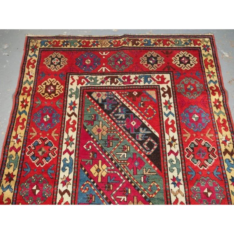 A good example of a Gendje long rug with multi coloured stripes in greens, blues, reds and yellow containing an interesting design of flowers, birds heads and rams horns. The rug is framed by a classic but simple floral rosette border.

The rug is