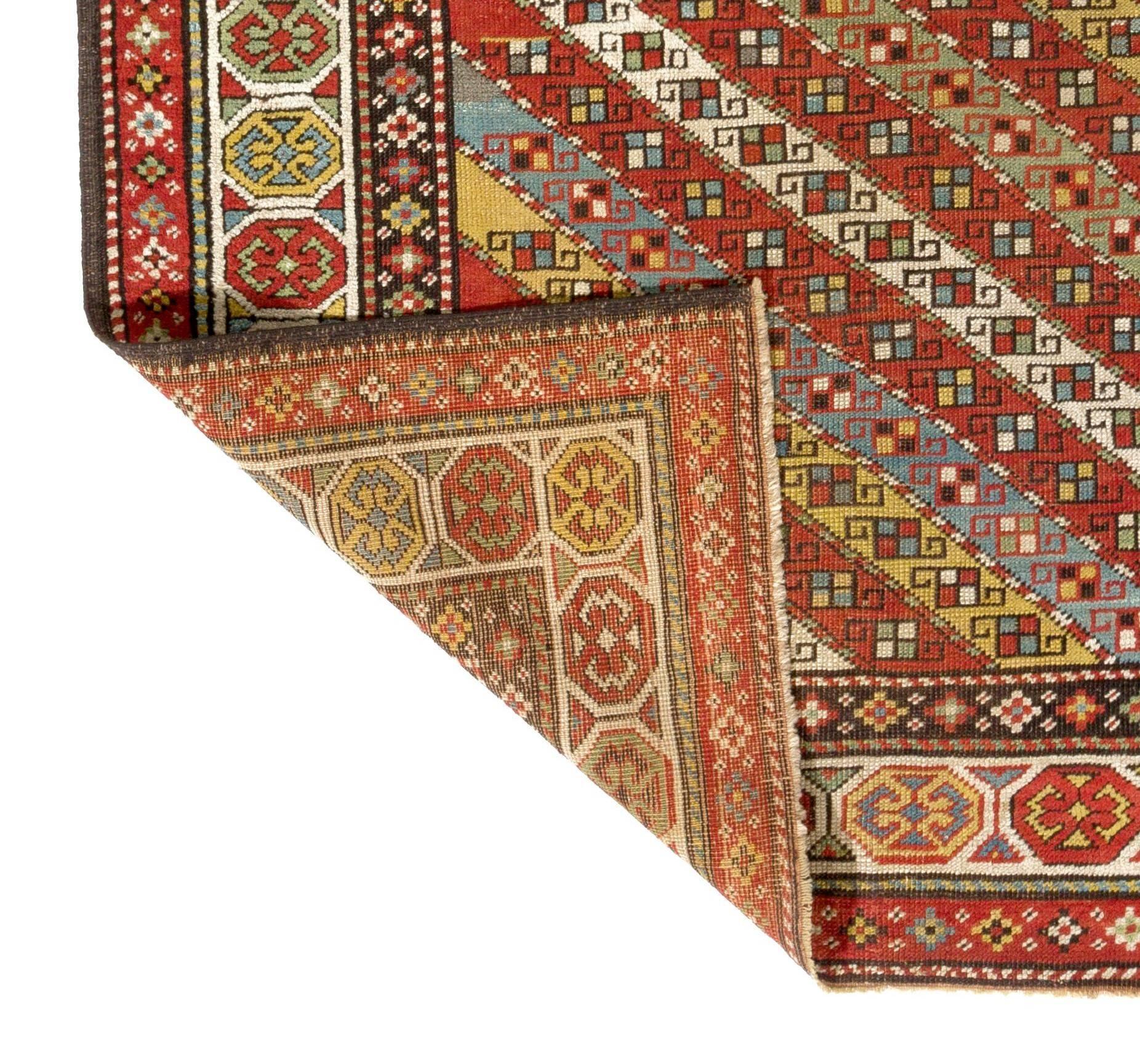 An exuberant and whimsical antique Caucasian Gendje rug from the 1870s featuring a clear and yet complex and meticulously woven design. The field is decorated with diagonal stripes that are each filled with several hooked wheel of life motifs and