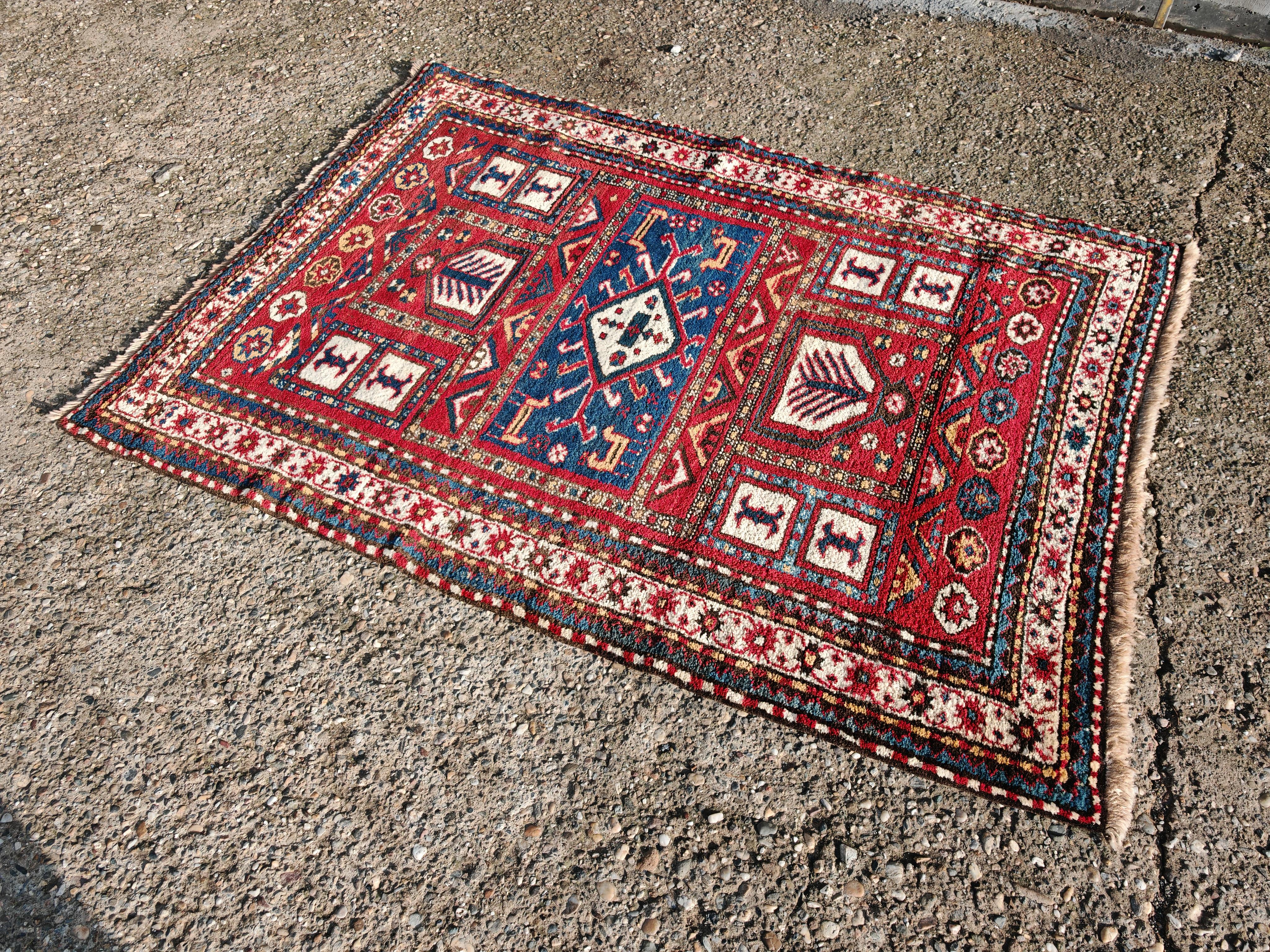 In diesem Angebot finden Sie einen atemberaubenden antiken handgeknüpften Karabagh-Teppich. Der in der Kaukasusregion gefertigte Teppich weist geometrische und florale Muster in Rot-, Blau- und Cremetönen auf. Die kühnen geometrischen Muster, die