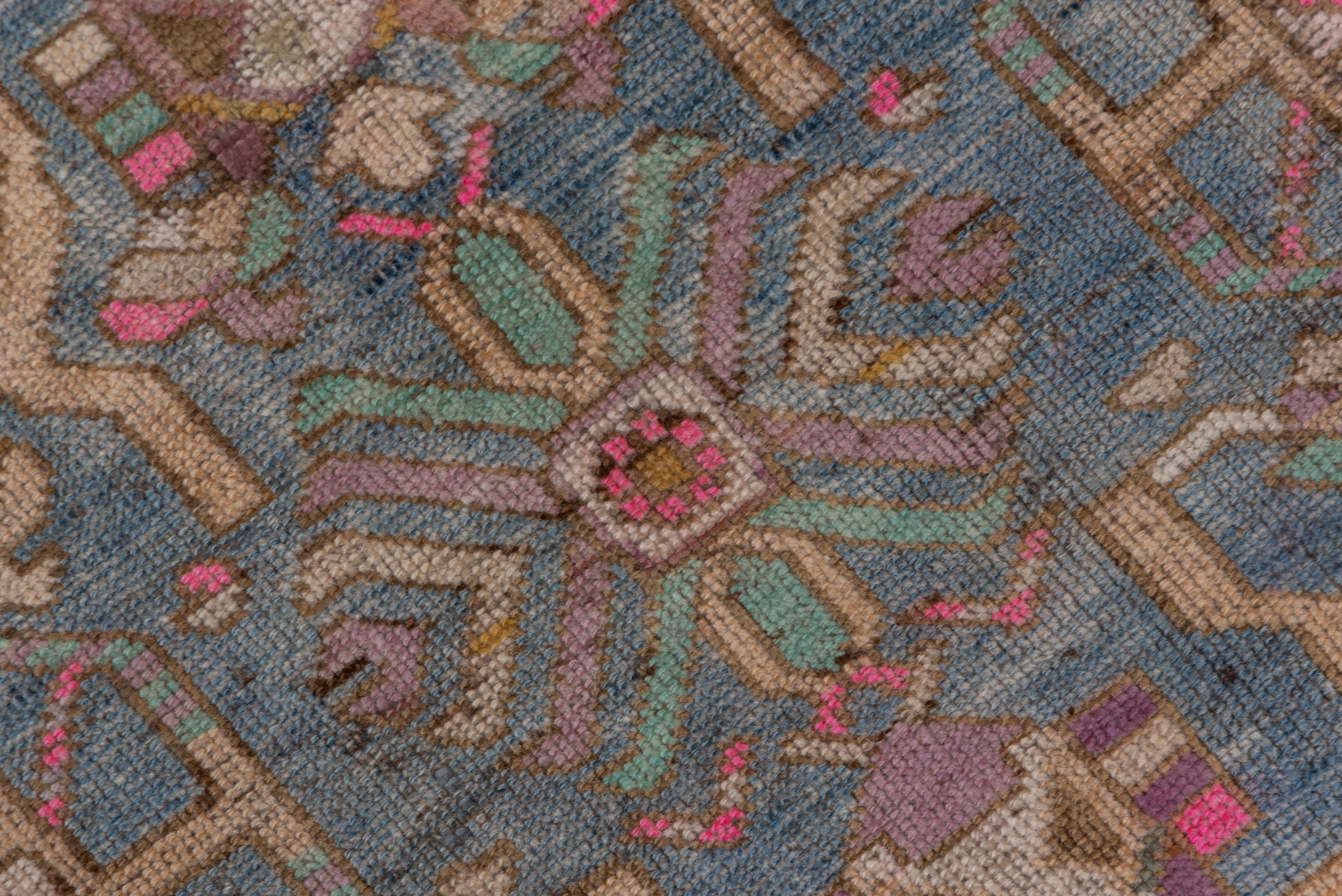 Thissouth Caucasian rug shows three touching large serrated pale blue-grey hexagons enclosing stylized palmettes and right angle vine sections, all on the open sandy straw ground, and set within an abrashed rosette and double vine/octagon rust-brown