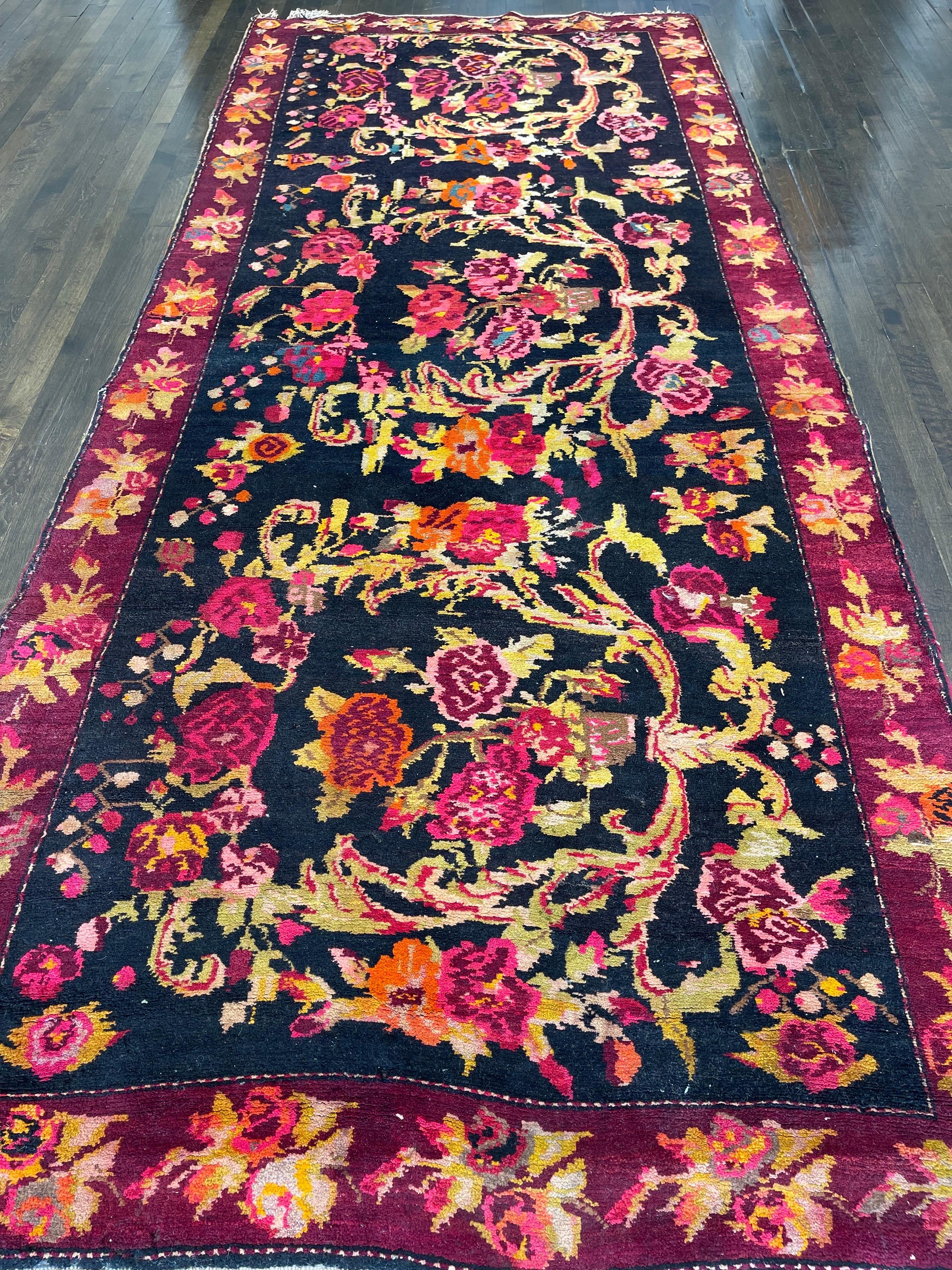 An outstanding example of Caucasian carpets woven in the European style created by Caucasian artisans, this corridor size runner features a floral composition on a black field surrounded by red/maroon borders. The Karabaghs in this style are
