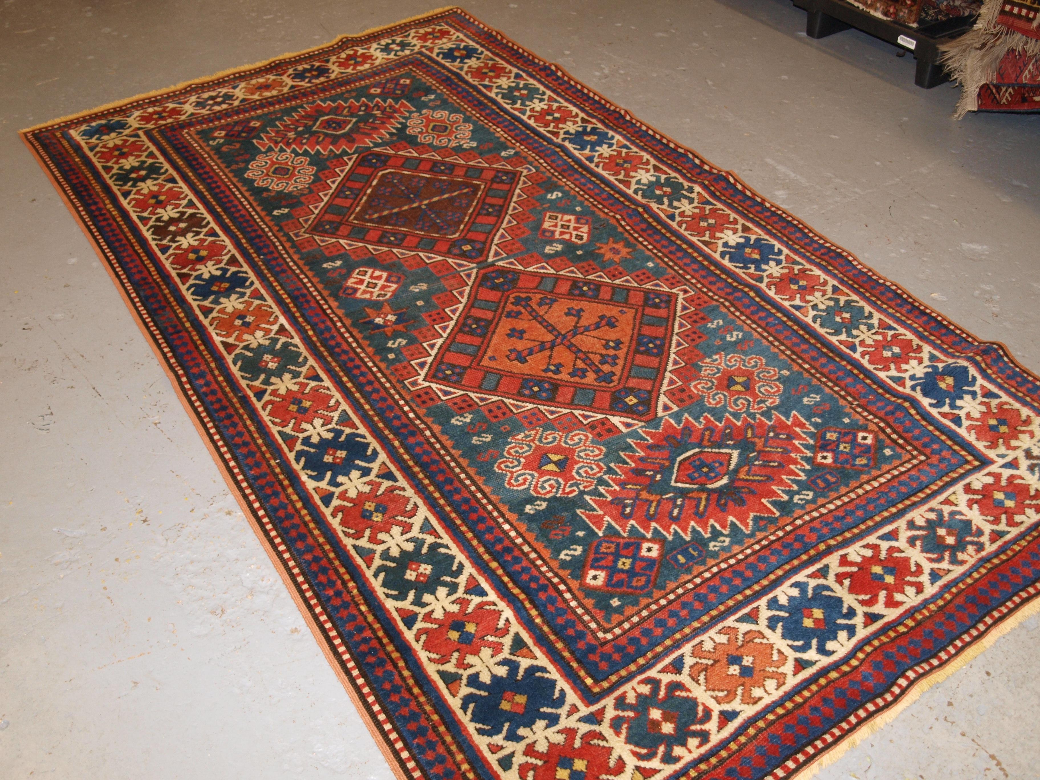Un bon exemple de tapis caucasien Karachov Kazak avec le motif traditionnel du médaillon lié, sur un fond vert clair. Le tapis est composé de quatre médaillons reliés entre eux sur un fond vert marin. Les combinaisons de couleurs en font un tapis