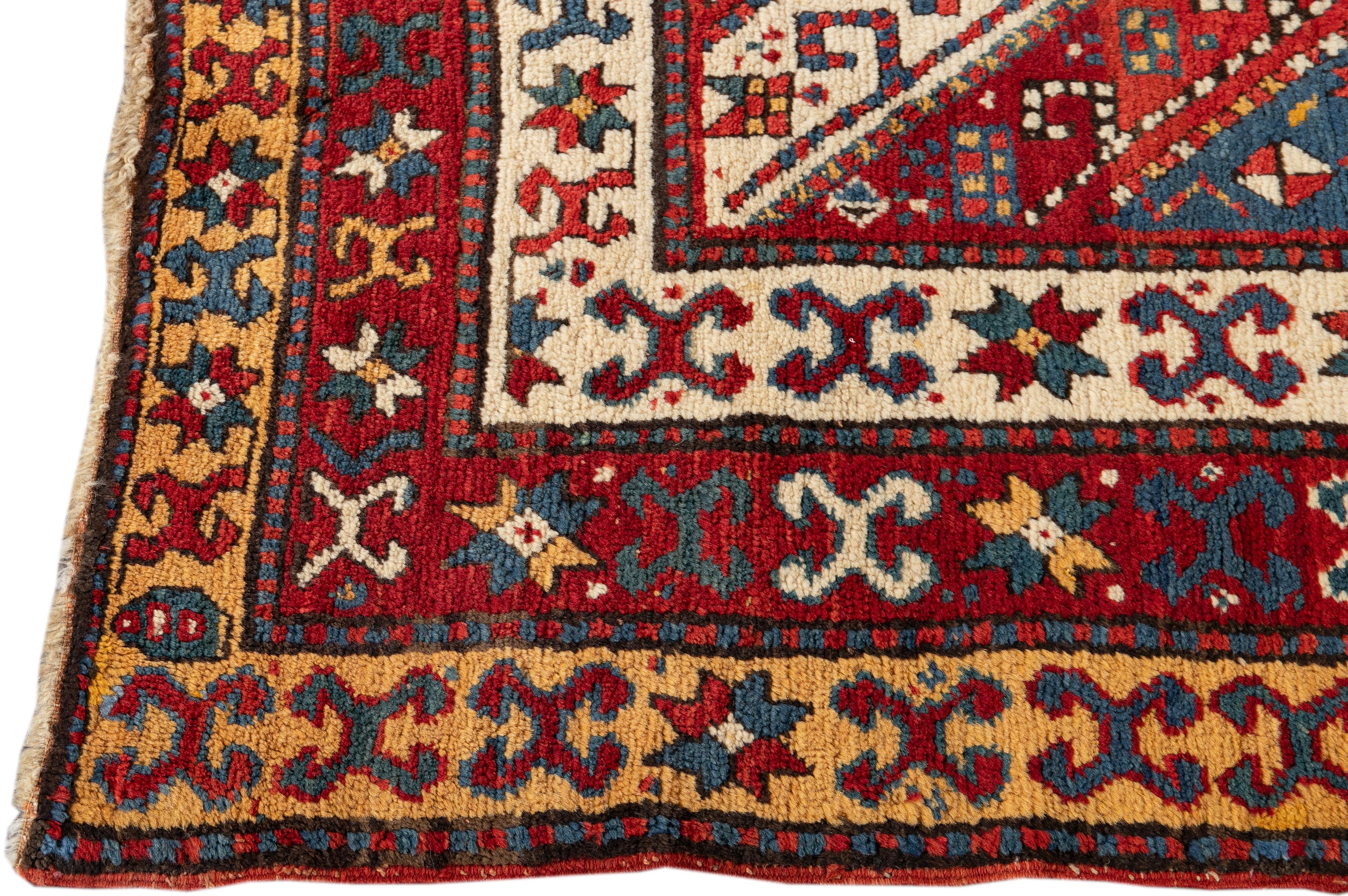 Beautiful antique Kazak hand-knotted wool rug with a red field. This rug has yellow, blue, and beige accents featuring an all-over geometric design.

This rug measures: 4'2
