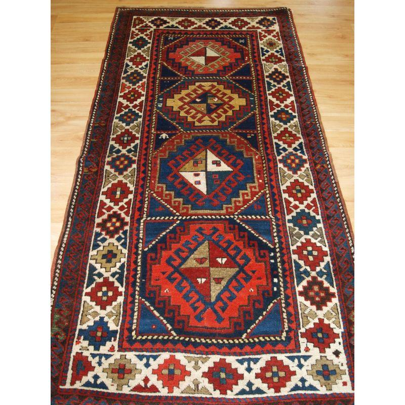 Antiker kaukasischer Kazak-Langteppich oder kurzer Läufer aus dem westlichen Kaukasus.

Ein sehr gutes Beispiel eines kasachischen Läufers oder langen Teppichs mit einem kräftigen, kühnen Medaillonmuster und klaren Farben.

Der Teppich ist in