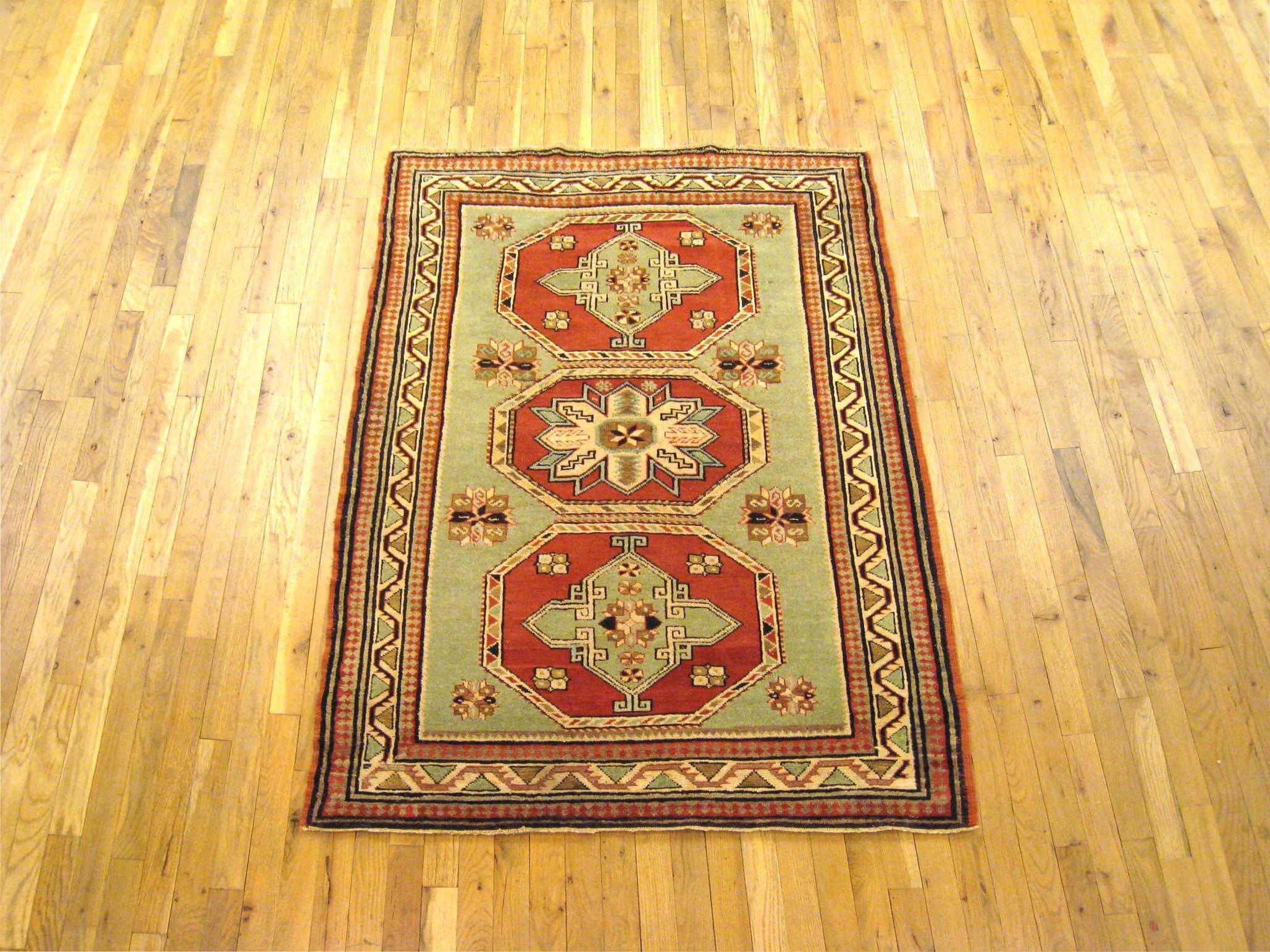 An antique Caucasian Kazak oriental rug, circa 1910-1920, size 5'3 H x 3'9 W. This handsome carpet has a multi-medallion design, with three lozenge medallions ensconced within the rarely found mint green primary field. The field is encased within a