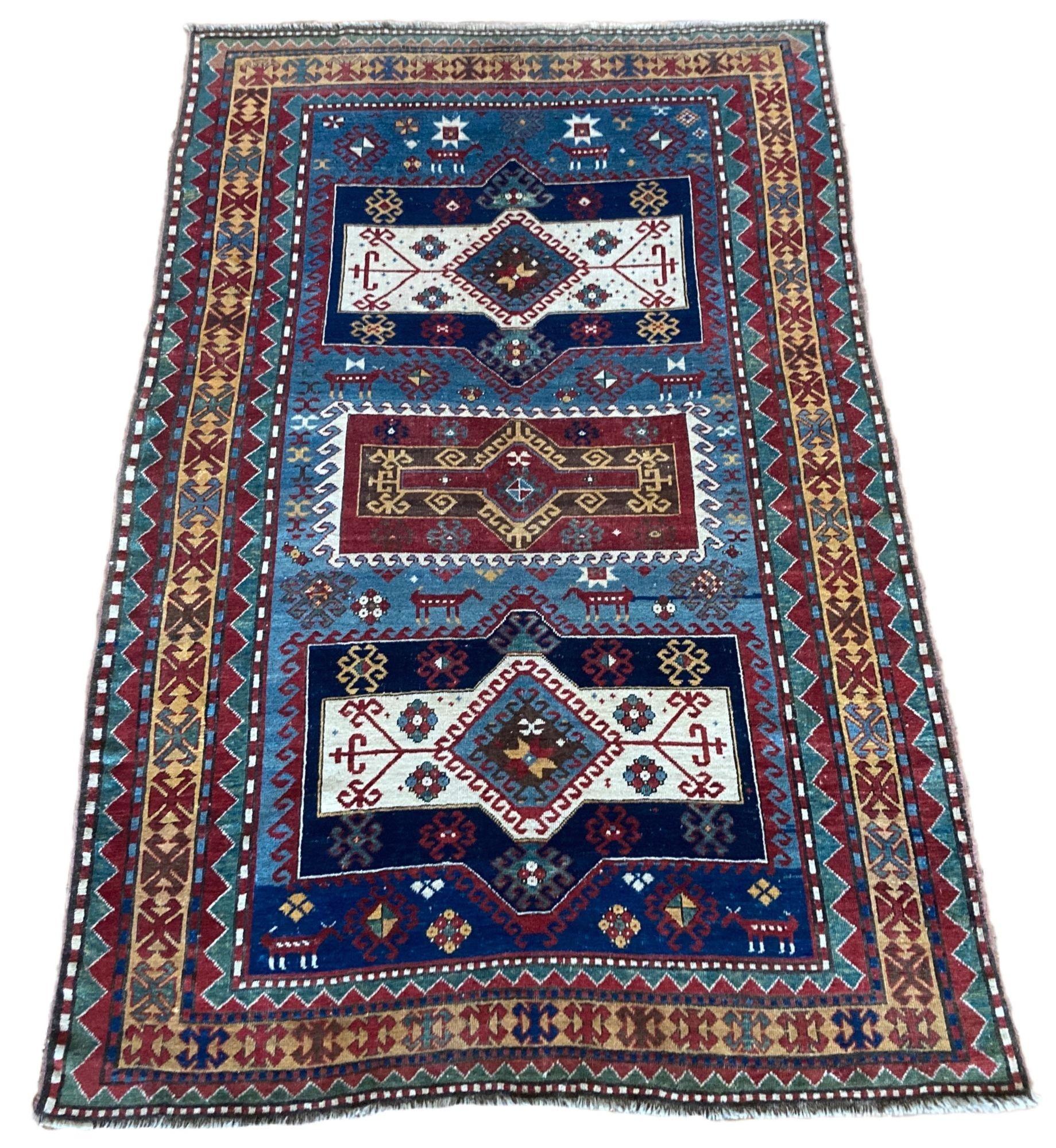 Superbe tapis kazak antique, tissé à la main dans les montagnes du Caucase, en Asie centrale, vers 1900. Le motif présente trois médaillons frappants sur un champ indigo et une bordure dorée inhabituelle. Remarquez les figures animales intéressantes