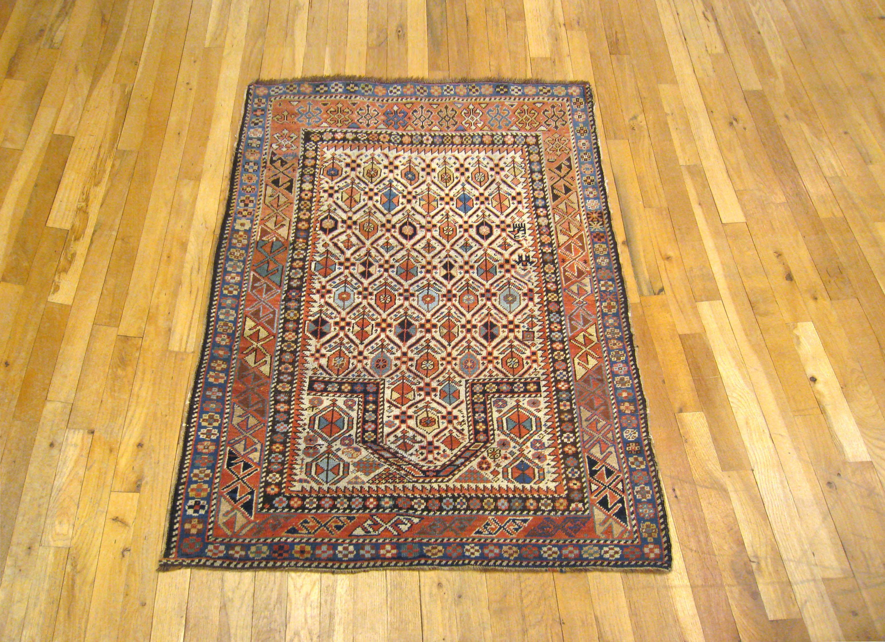 An antique Caucasian Kuba meditation rug, size 4.6 x 3.1, circa 1890. This fine hand-knotted wool oriental rug features a repeating lozenge design on a seldom found ivory field, with a prayer arch at one end. The central field is enclosed within a