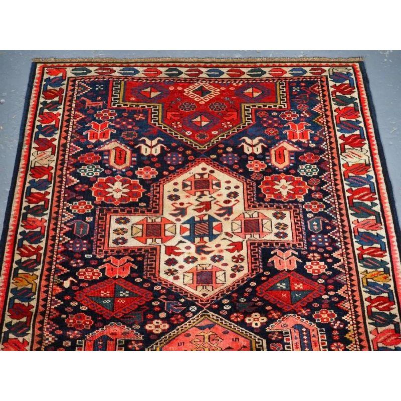 A colourful rug that is probably from the Kuba region of the Eastern Caucasus. The three and a half cruciform medallions are on a dark indigo blue field which is filled with an array of Caucasian design elements. The border is of a simple yet
