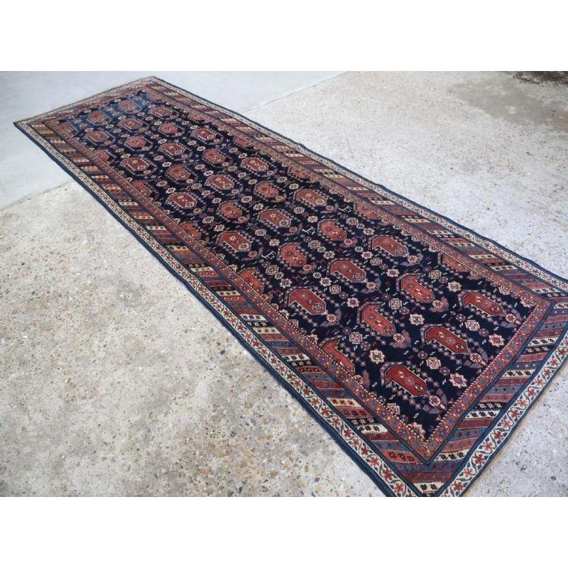 An antique Caucasian Kuba region Shirvan runner, with all over large boteh design. The indigo field is filled with large boteh, flowers, stars and tribal design elements; there is even a row of small animals crossing the runner. The soft colours