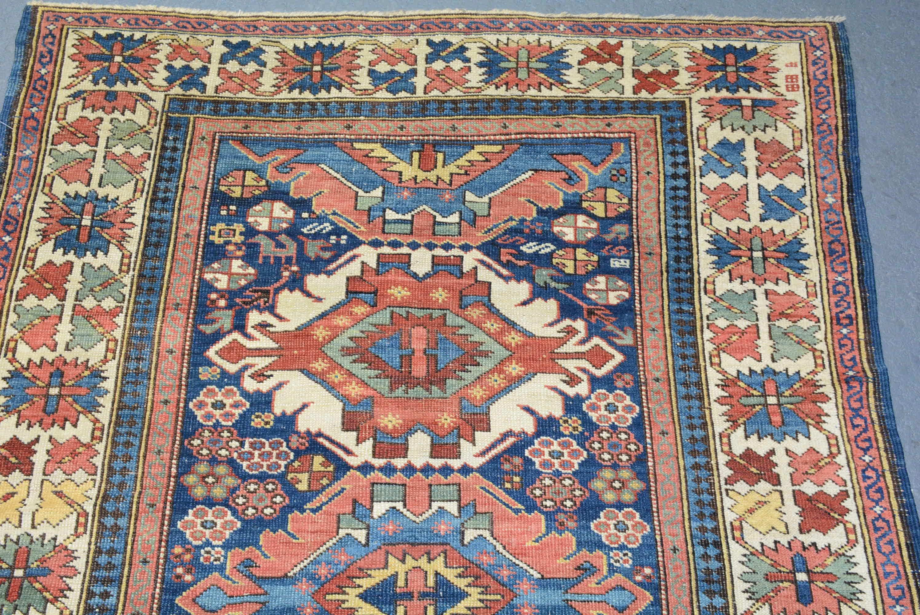 A late 19th Century Caucasian Kuba rug with a bold pattern of geometric medallions on an indigo field within an ivory 
