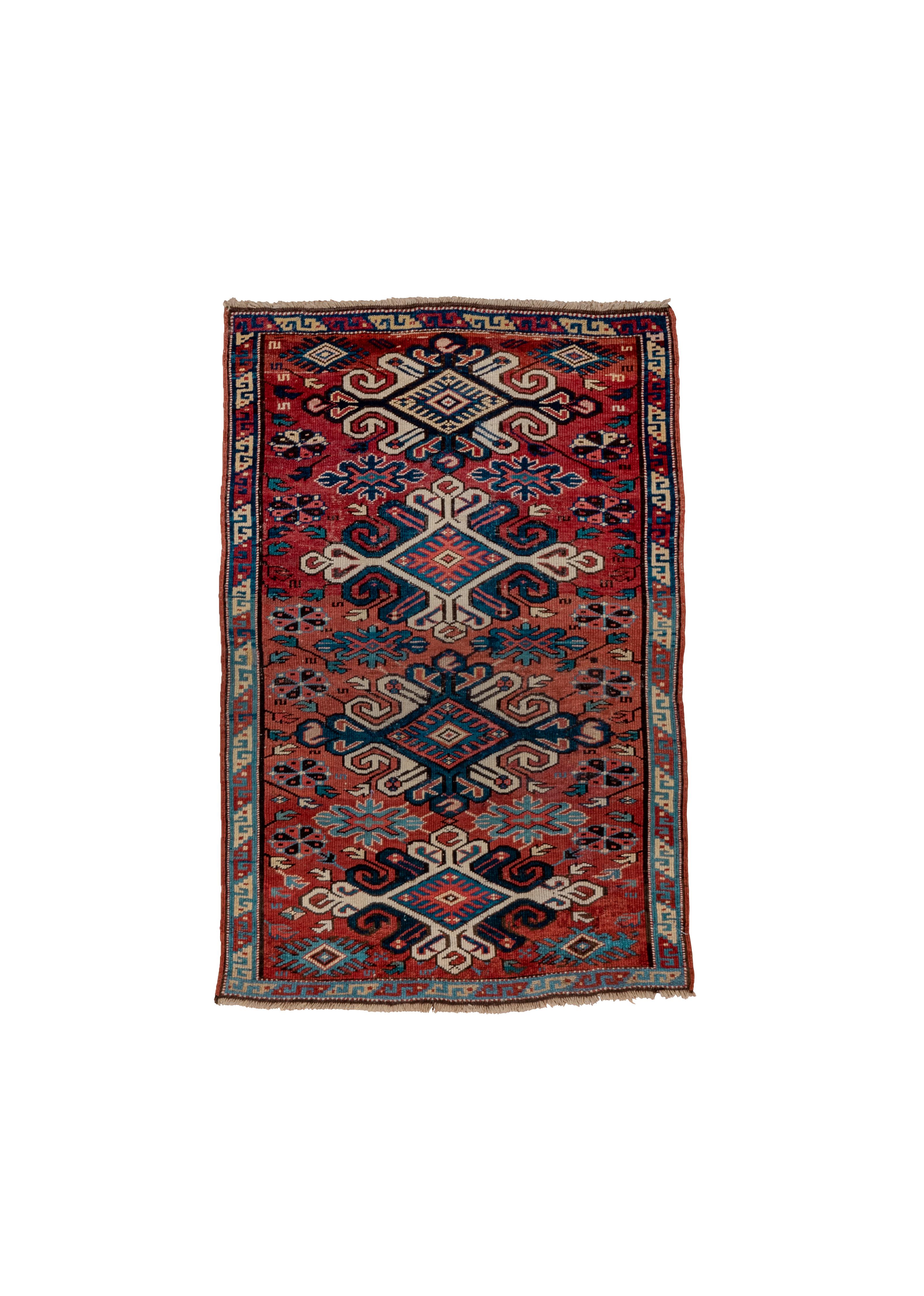 Cette pièce de laine nouée symétriquement présente deux grands losanges avec des extensions en forme de cœur ouvert, placés entre des losanges imbriqués avec des accents doublement enroulés.  Une multitude de rosettes, d'étoiles et de fleurons, le