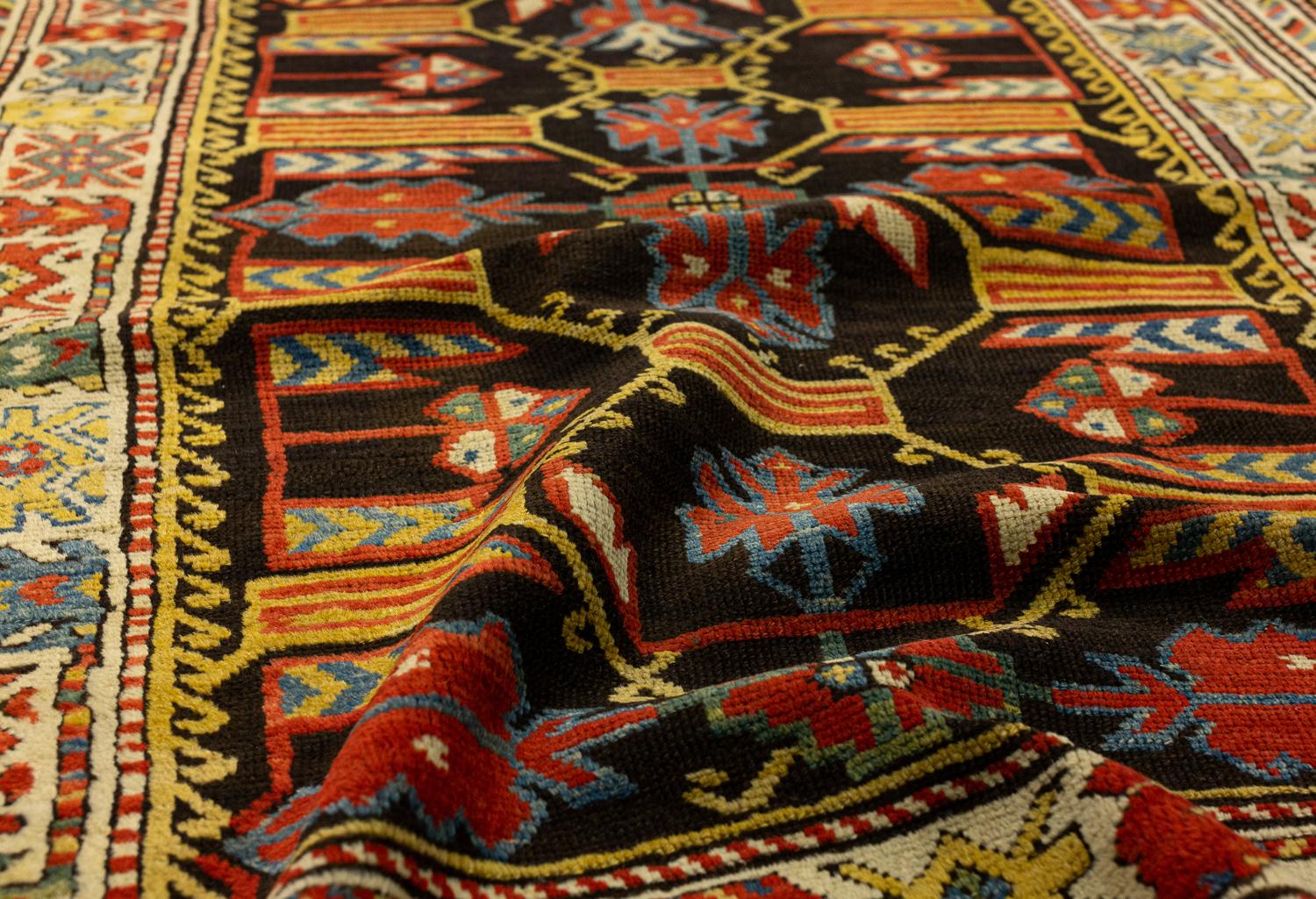 This is an antique Kuba rug woven in the northern part of the Caucasus mountains and was woven during the end of the 19th century. It has a unique all-over highly geometric design that has saturated colors on a black background creating a dramatic