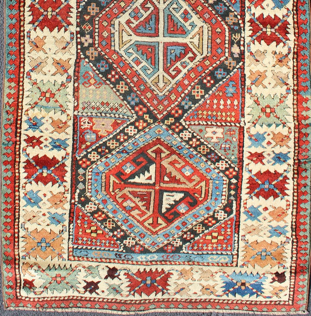 Antique Caucasian Kuba Rug with Intricate and Complex Design.
This beautiful piece is a late 19th century Kuba rug with an indigo blue field beneath a geometric vinery trellis featuring bold polychrome medallions and stylized leaves. The ivory frame