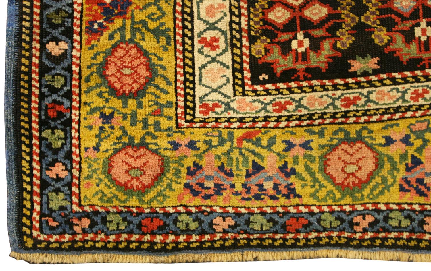 An antique Seychour rug, South Caucasus. The charcoal-black field with overall diagonal rows of stylized multicolored bold and serrated floral boteh. In the sandy-yellow border of stylized polychrome sunburst palmettes and angular vine between ivory