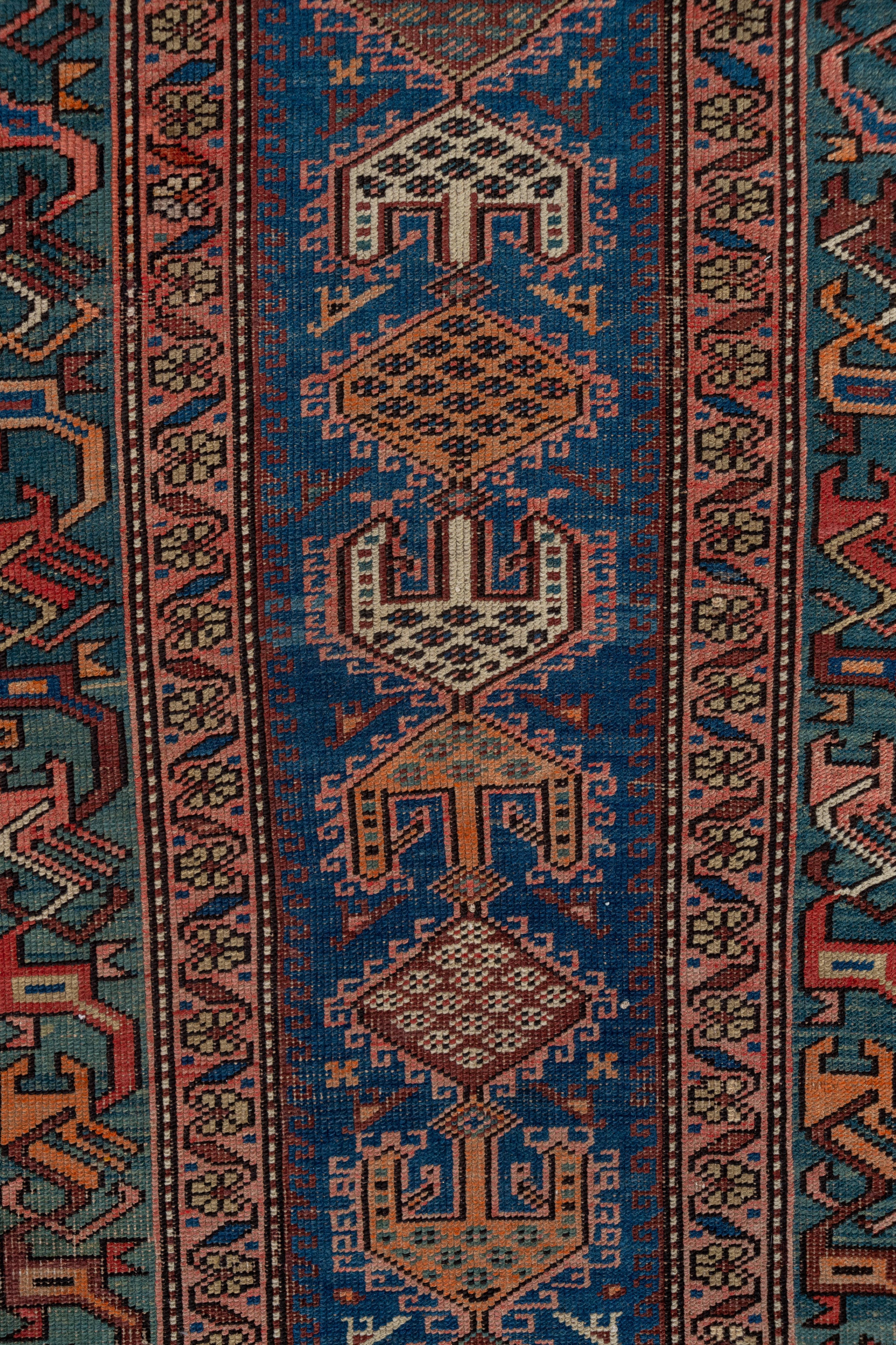 From the Caucasus or northwest Persia, this medium blue field runner has a lozenge and trident pattern in orange, ivory and blue-green, within a deep blue-green 'dragon vine' border. Small birds are set pairwise in the field.
