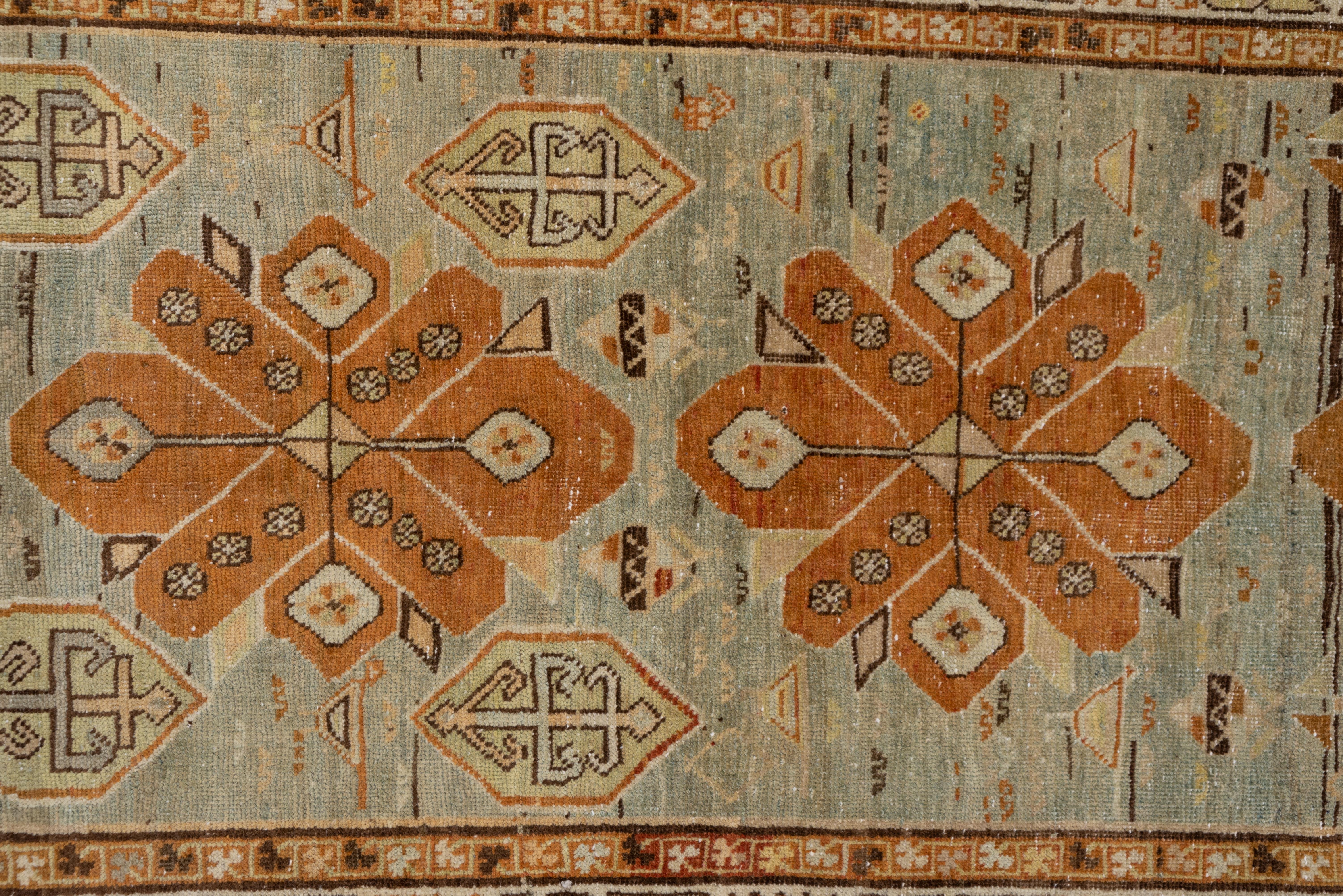 This runner has a pale grey field that displays six rust rosette-decorated octofoils with smaller hexagonal plaquettes and hand grenade botehs. The cream crab border is detailed in soft red, straw, light green, khaki and brown.