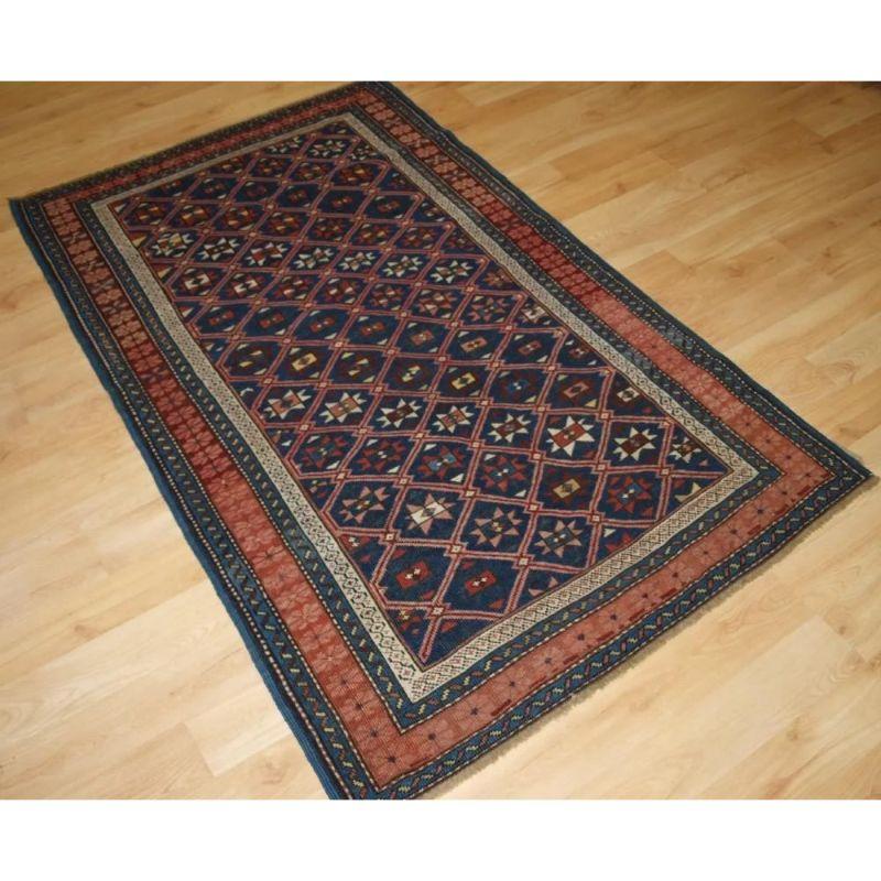 This charming rug has a dark indigo blue field covered with a fine diamond lattice, with each diamond containing an eight pointed star. The stars are of differing colours and designs. The rug has a beautiful border in typical Seichur colouring with