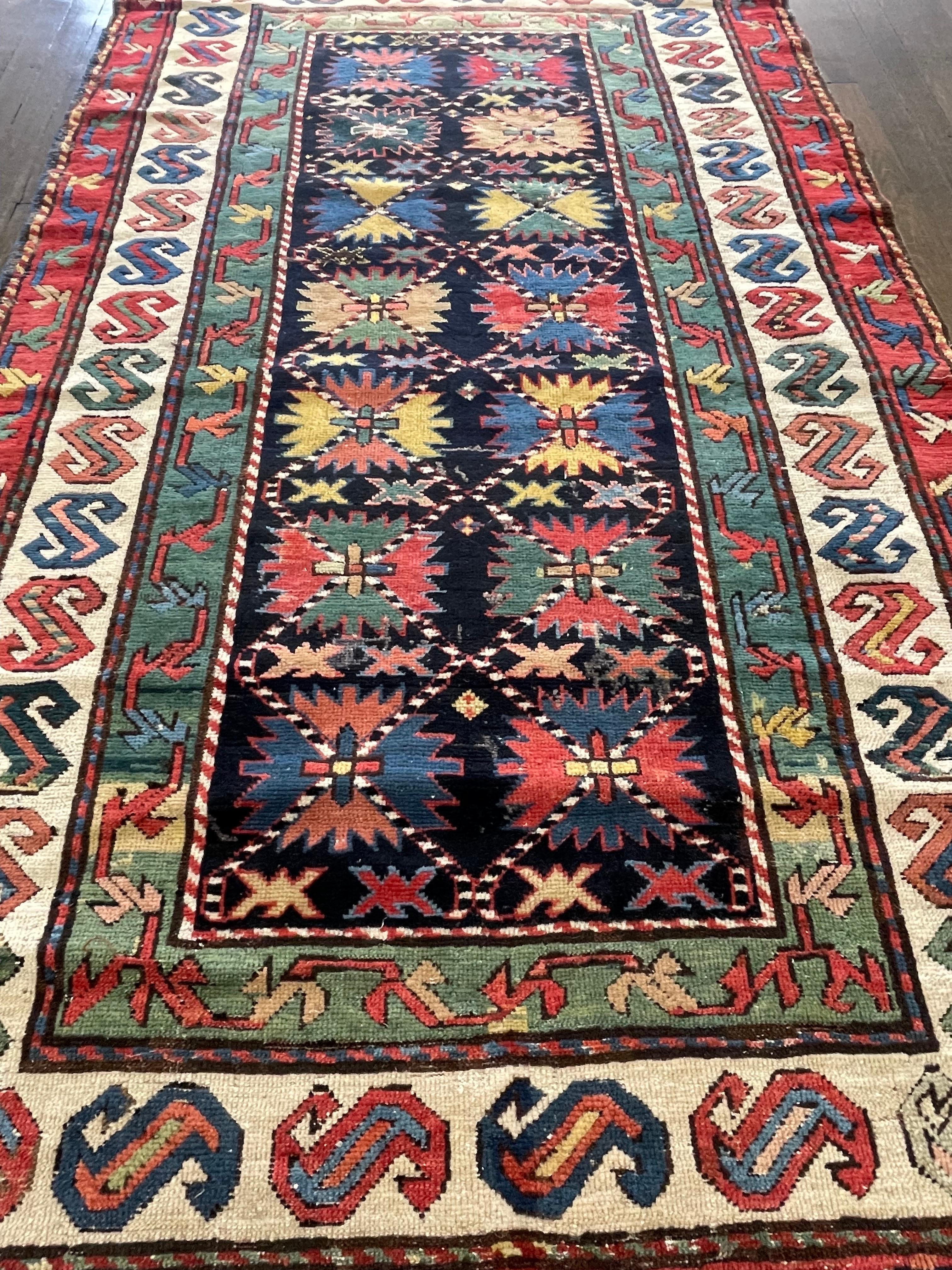 A spectacular antique caucasian carpet decorated with an unusual twenty- point Lesghi star. The rug features boldly contrasted colors of indigo blue for the field and three wide borders of green, Ivory and maroon red respectively. Few caucasian rugs
