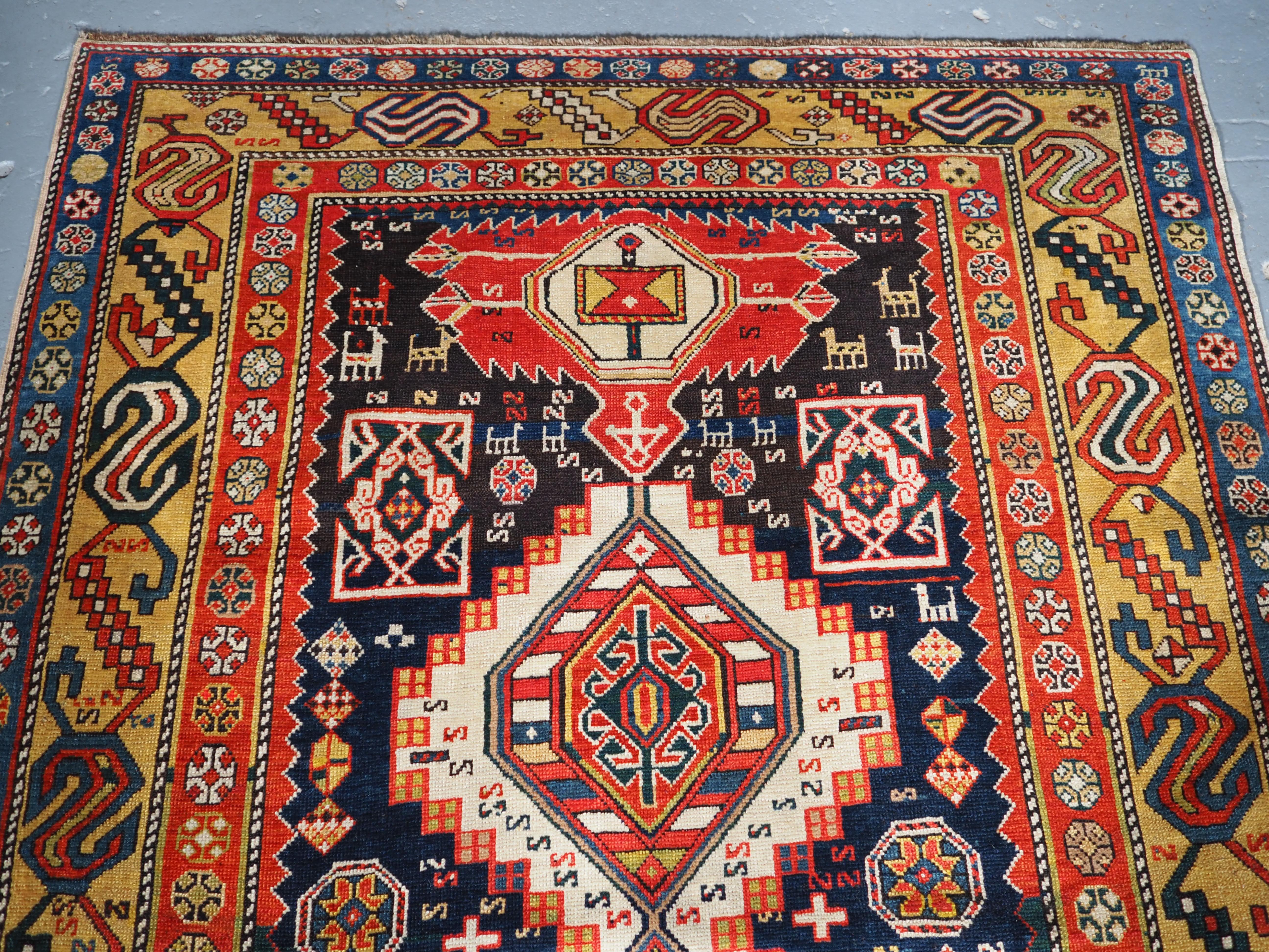A very good Shirvan rug with the field filled with a single row of four large linked medallions, with the flattened floral design at the ends. This example has outstanding colour and the dark indigo blue field is covered with Caucasian design
