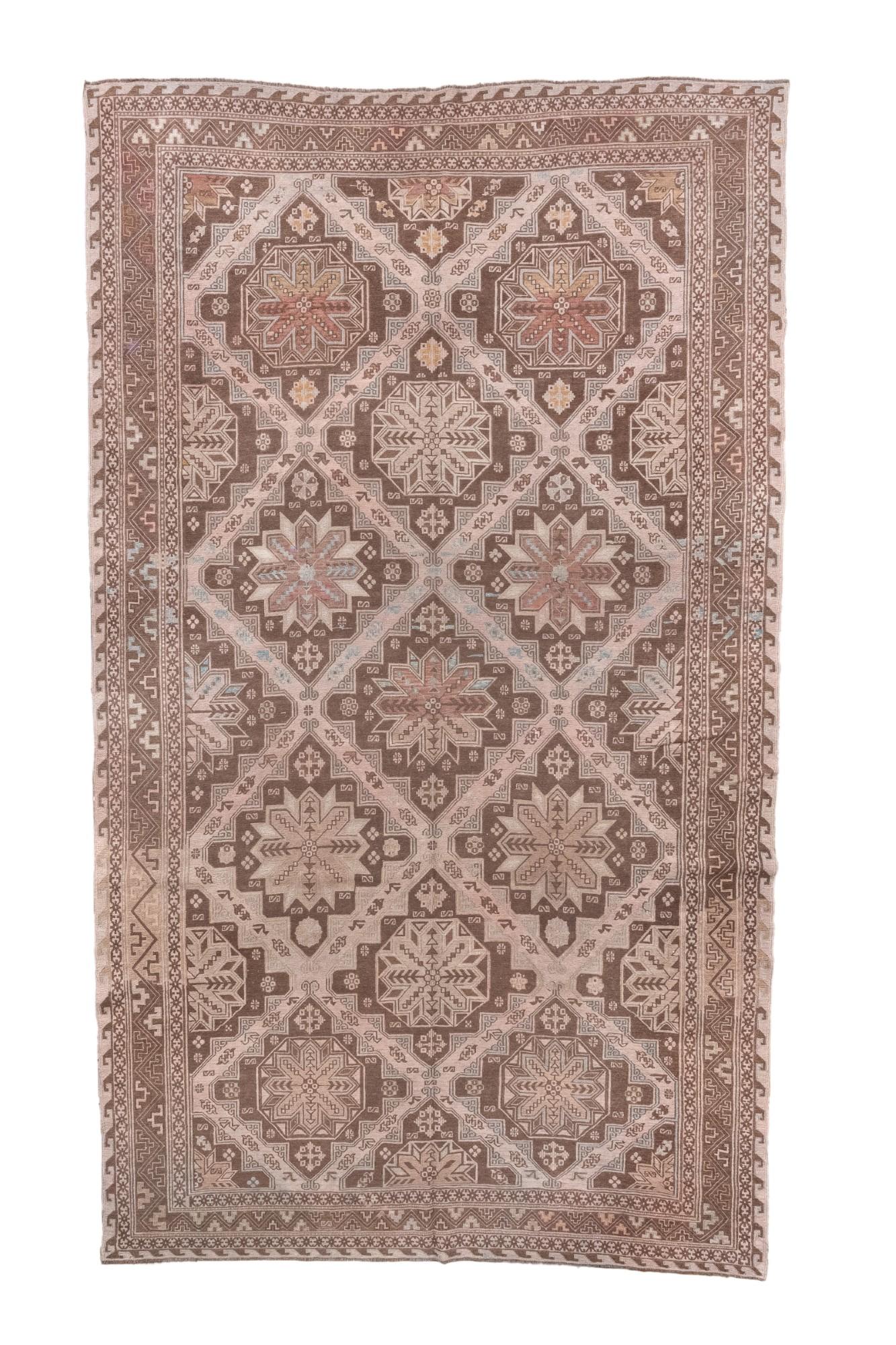 Questo antico tappeto Sumak caucasico, tessuto intorno al 1920, è caratterizzato da uno splendido reticolo...
con una serie di medaglioni a stella stilizzati disposti in un motivo all-over.
Realizzato nei toni terrosi del marrone, del tortora e