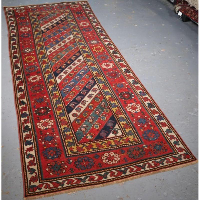A good example of a Talish long rug with multi coloured stripes in greens, blues, reds and white containing repeat small boteh design. The rug is framed by a classic but simple floral rosette border typical of the Talish region. The inner yellow