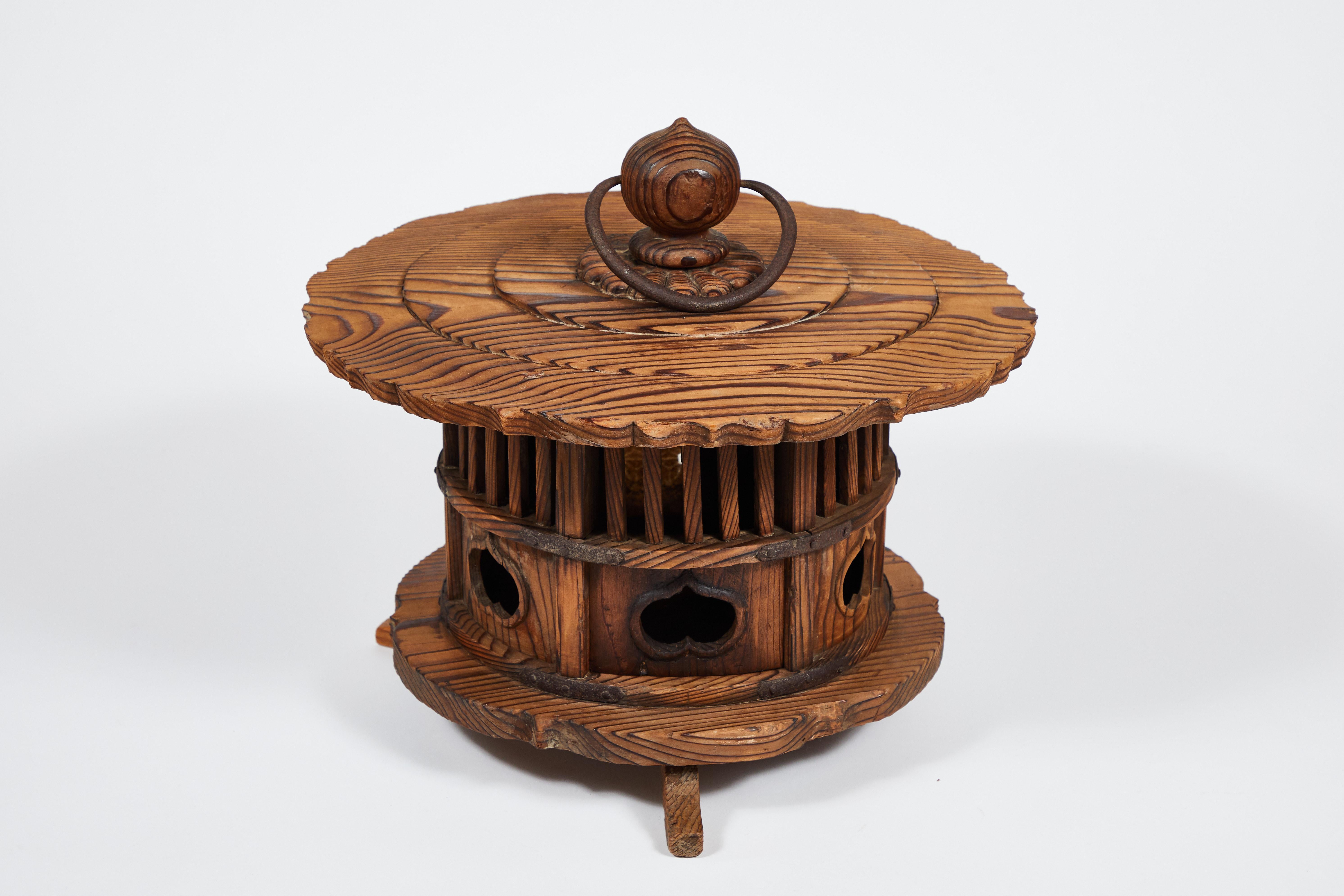 This is a hand carved cedar wood (jindai sugi) pagoda-stype round andon or lantern with bronze fittings and ring handle, circa 1860-1880 (Edo to Meiji period). Hand carved with big dramatic grain and a rippling roof, this was a garden or temple
