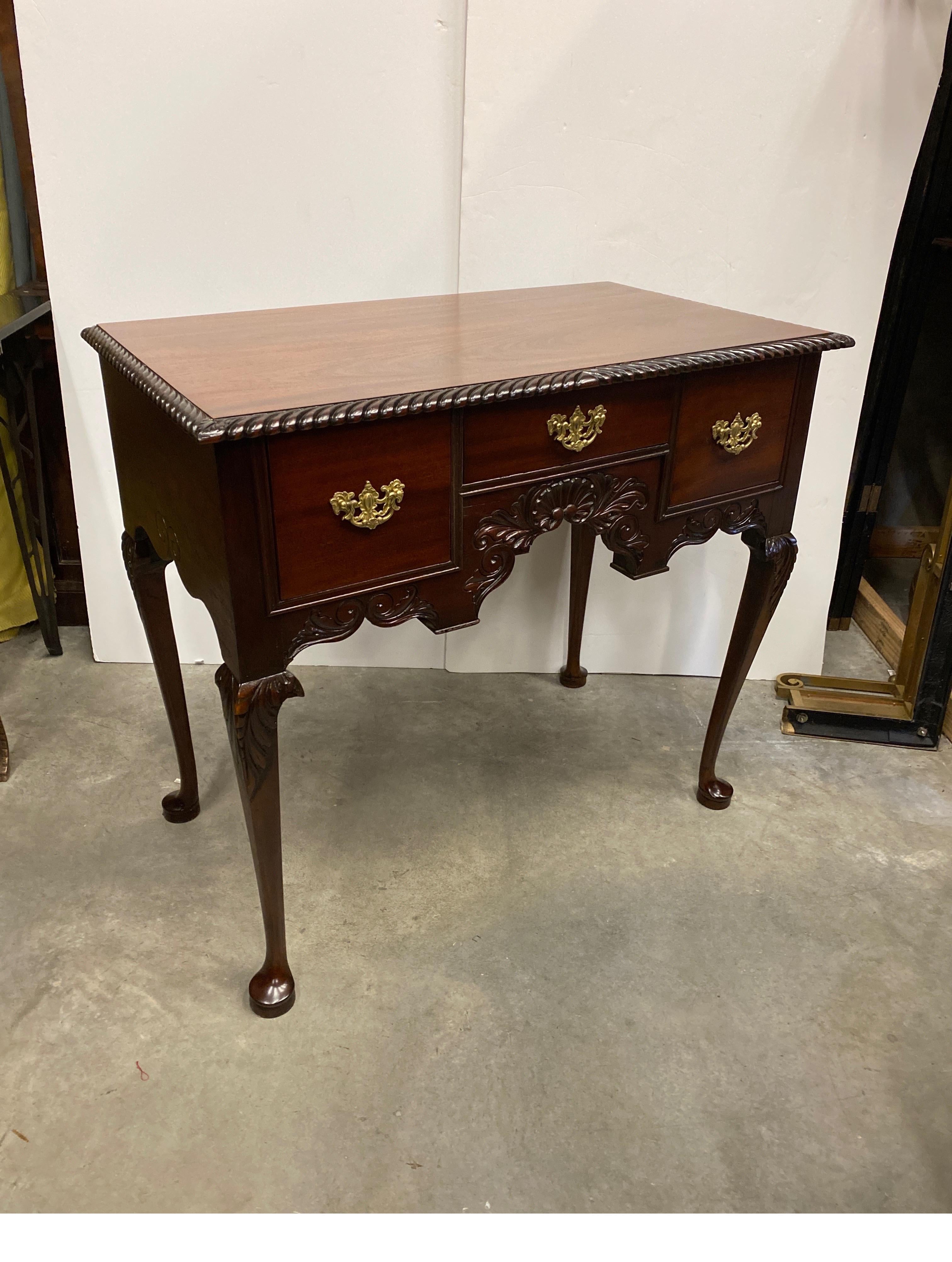 A classic Centennial hand carved mahogany lowboy.  The hand carved details on the front, the gadrooned edge at the top and delicate carvings on the legs, the finish has been professionally cleaned and restored with the original gilt handles. 38.5 by