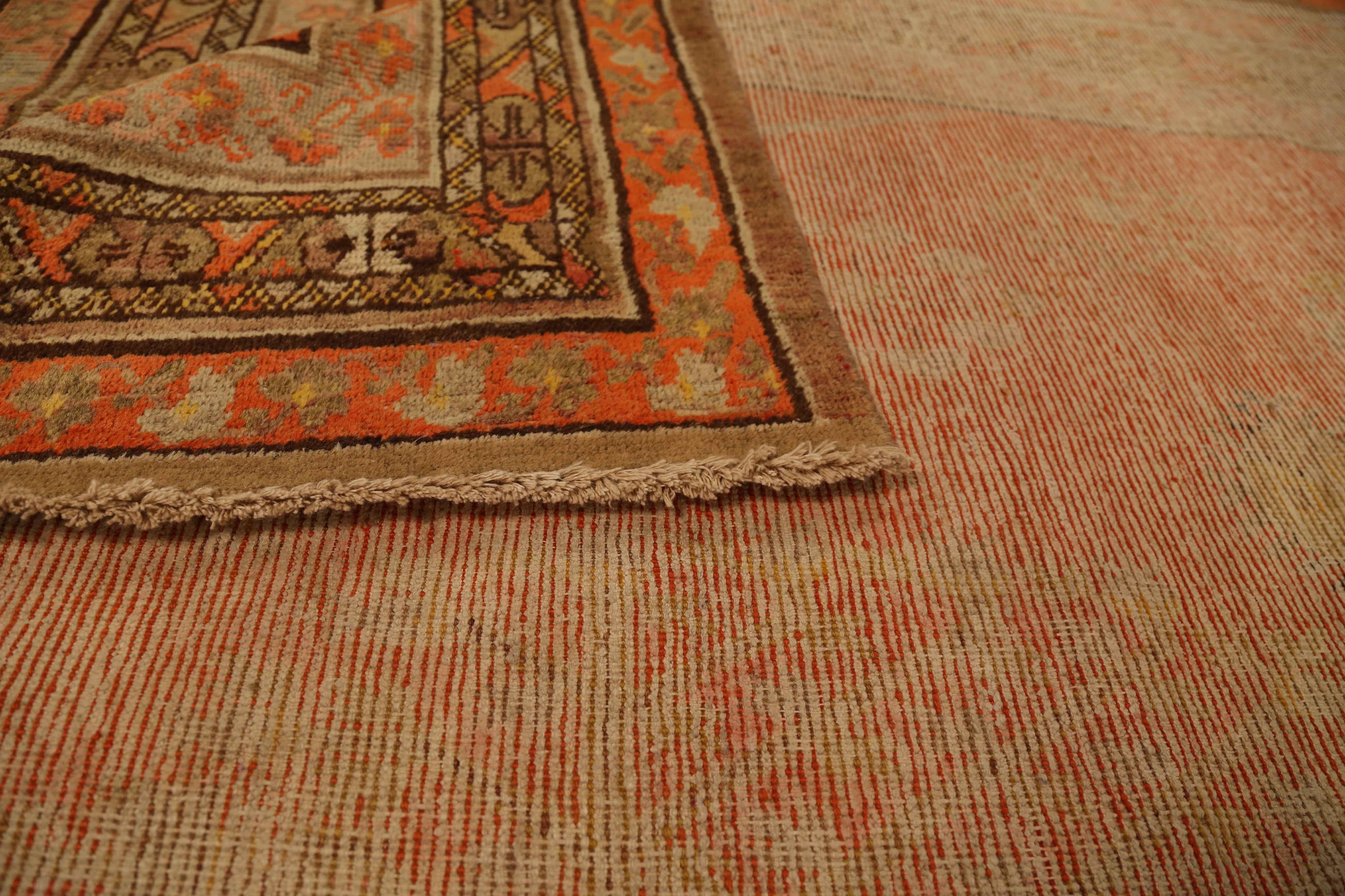 Tapis ancien d'Asie centrale fait à la main à partir de laine fine et de teintures végétales vibrantes. Il présente un champ central ouvert de couleur rouge recouvert de motifs géométriques jaunes et verts. Comme la plupart des tapis fabriqués au