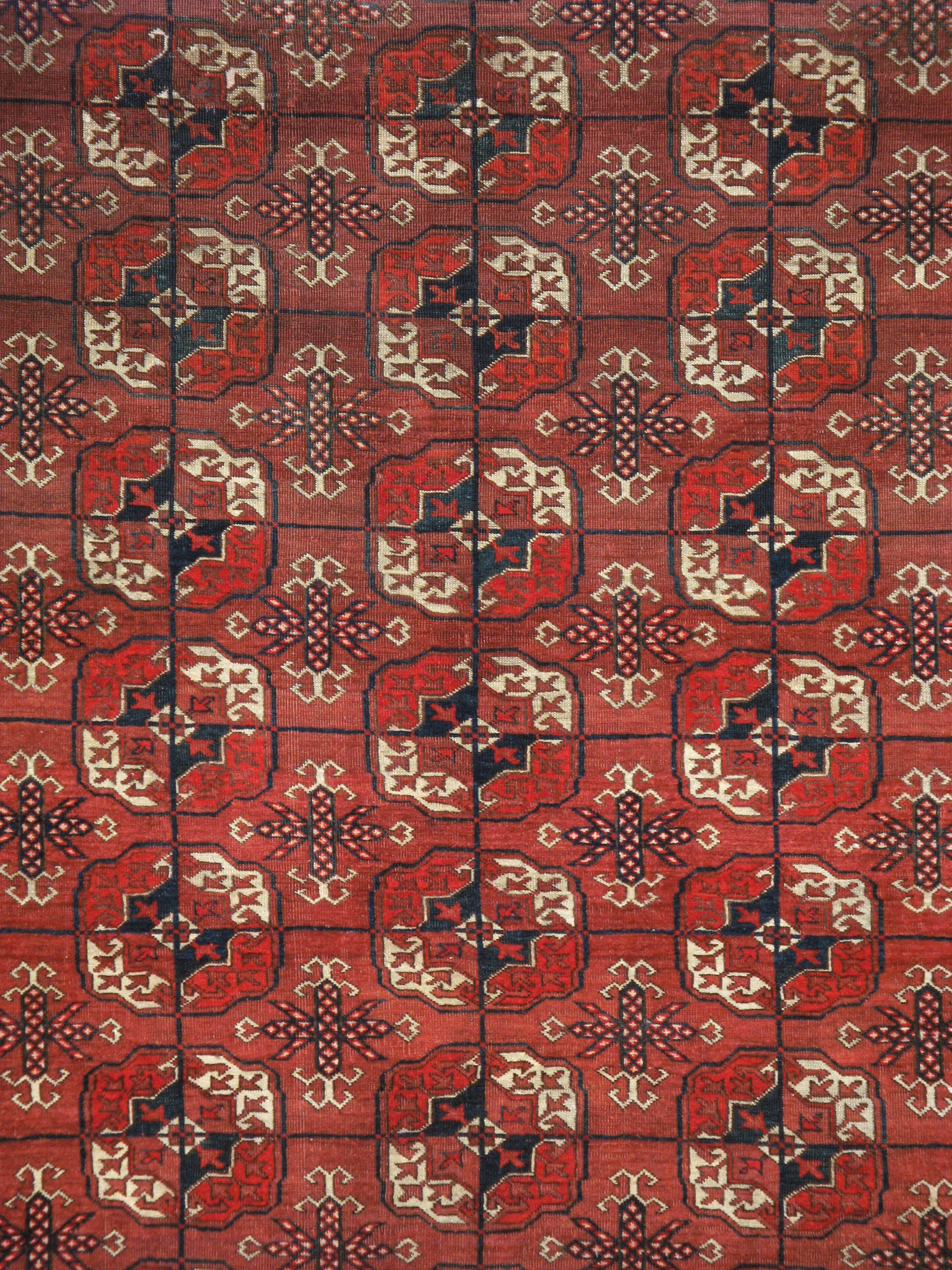 Un ancien tapis Tekke d'Asie centrale. Provenant de la plus importante tribu de tissage turkmène du Turkménistan, ce tapis nomade rouge sang présente cinq colonnes de onze médaillons gul (fleurs) caractéristiques dans une bordure de couleur assortie