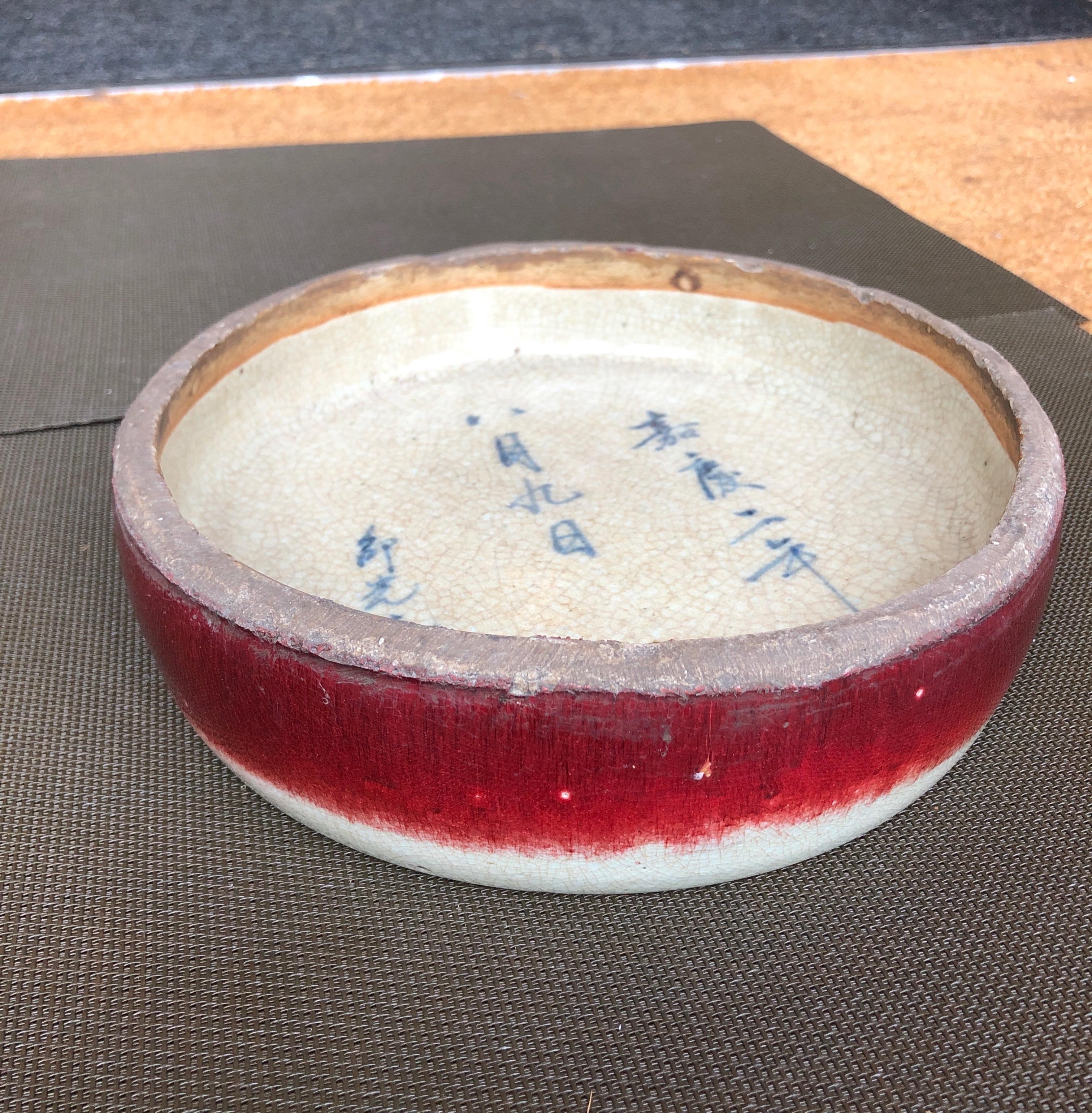 An unusually large and heavy antique Chinese ceramic brush washer with three lines of blue hand painted Chinese characters and a bold red stripe on the outside. A piece of history in a beautiful package. China, c. 1880 or earlier.