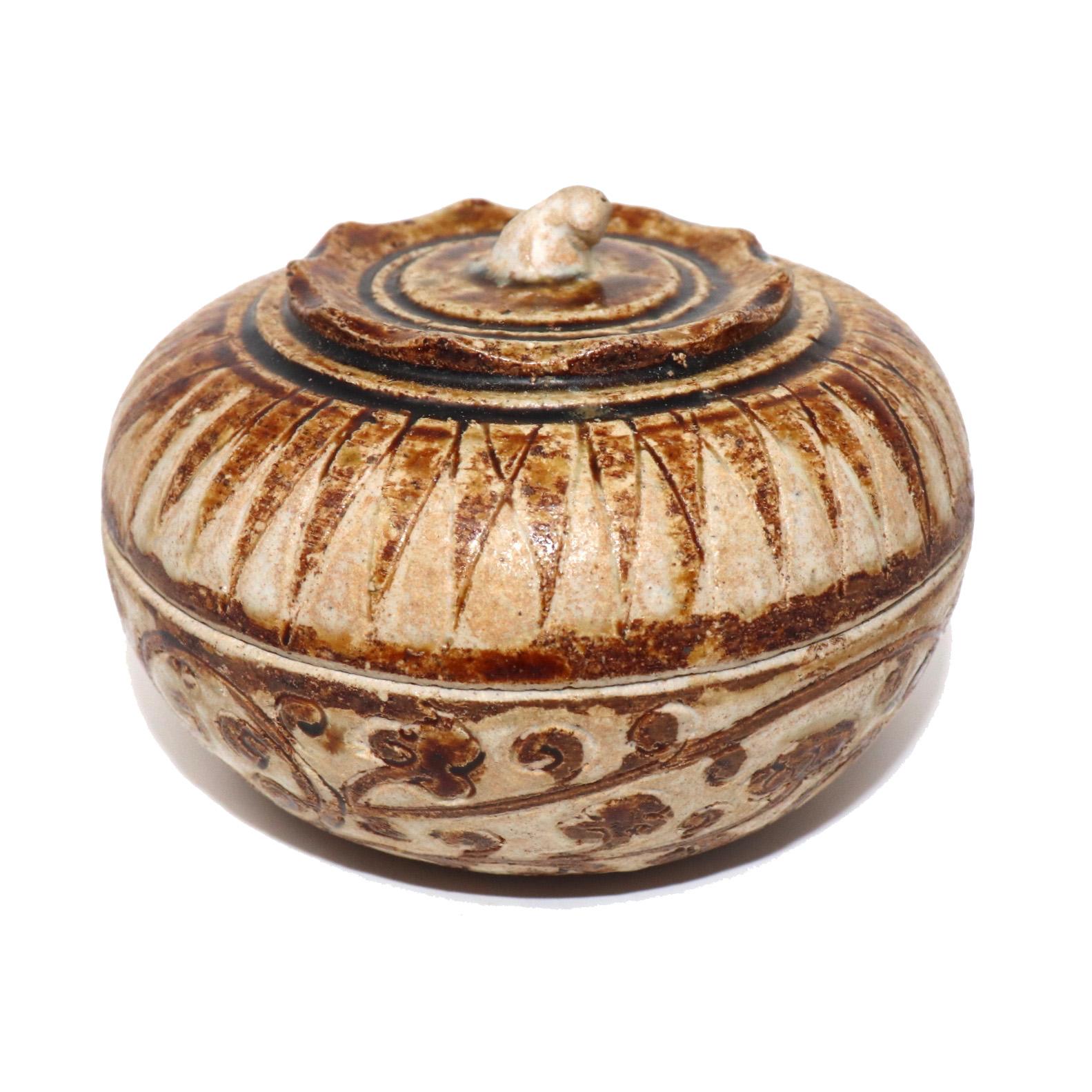 Antique ceramic covered box from the Sawankhalok kilns, Thailand of squat globular persimmon form with pinched sepal ridge and  curled stem finial top decorated in a caramel brown and translucent white glaze on the stoneware biscuit in a saw tooth