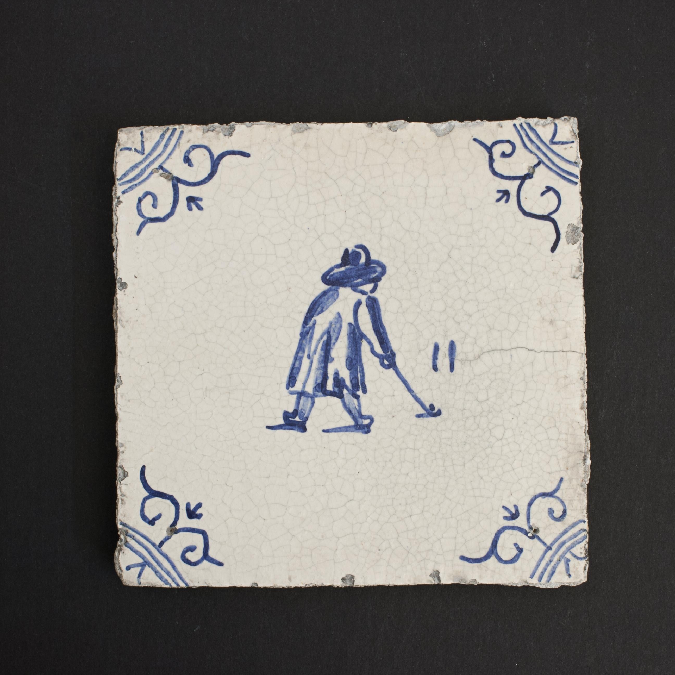 Azulejo holandés Delft Kolf.
Un azulejo de golf holandés temprano de delft azul y blanco - pintado a mano con una escena de Kolf que representa a un jugador de Colf/ Kolf. La imagen azul está sobre un fondo blanco roto con un diseño floral