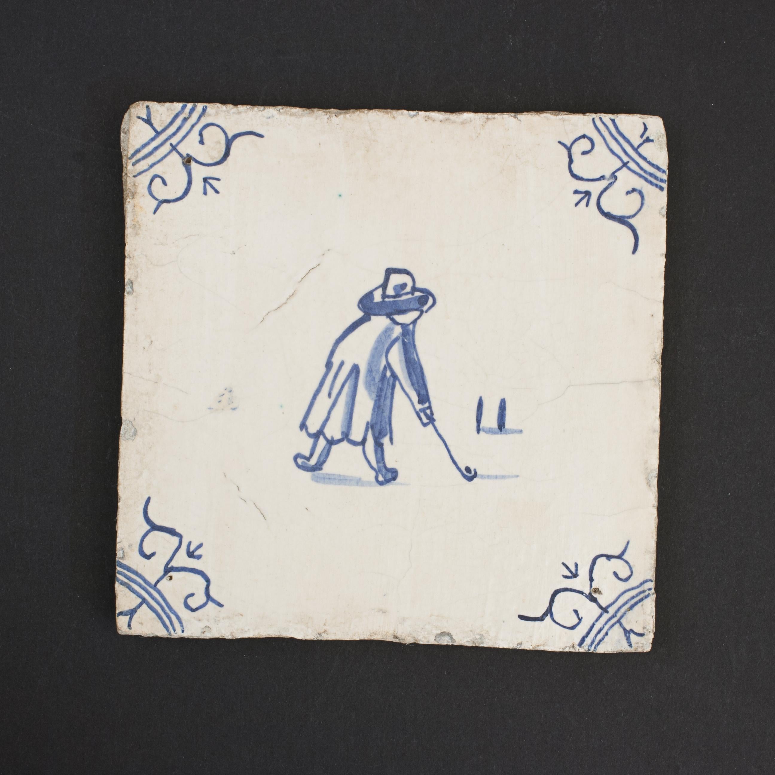 Azulejo holandés Delft Kolf.
Un azulejo de golf holandés temprano de delft azul y blanco - pintado a mano con una escena de Kolf que representa a un jugador de Colf/ Kolf. La imagen azul está sobre un fondo blanco roto con un diseño floral