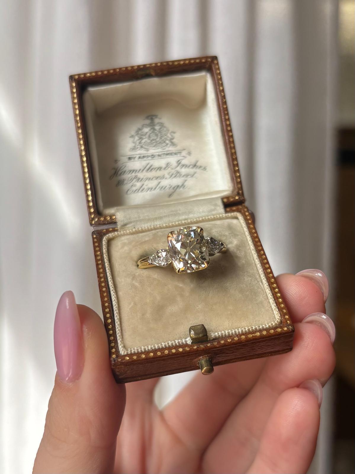 A beautiful antique 3.31ct old cushion cut diamond three stone ring set in 18k yellow gold and platinum. 

The ring is centrally set with a stunning antique old cushion cut diamond which is securely four claw set in yellow gold. The diamond is then